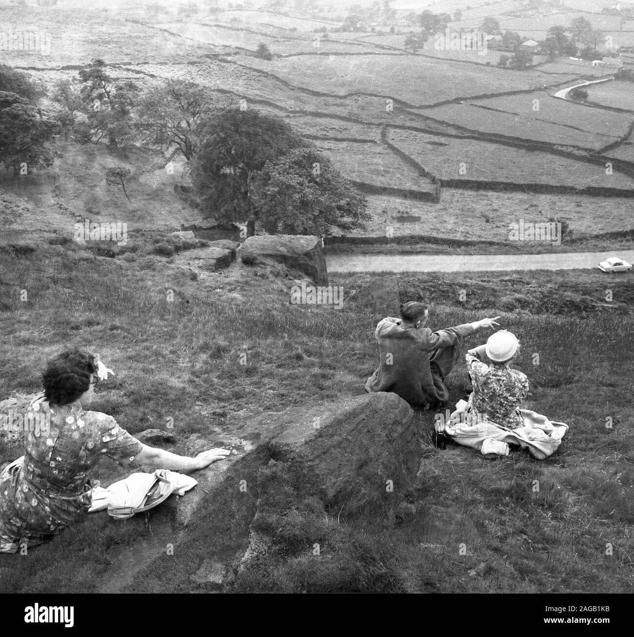 1950s, historical, three adults sitting on a hillside overlooking the valley below at Long Mynd, Shropshire, England UK.  A heath and moorland plateau, in 1965 large areas of Long Mynd - almost all its upland area - were brought by the National Trust and designated as an area of outstanding natural beauty (ANOB). Stock Photo