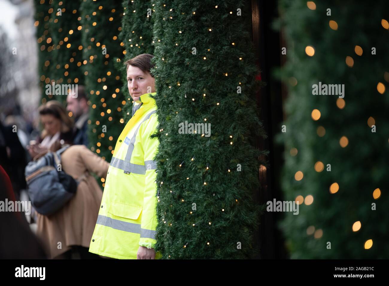 Selfridges staff member standing between the Christmas trees outside Selfridges and looking into the camera Stock Photo