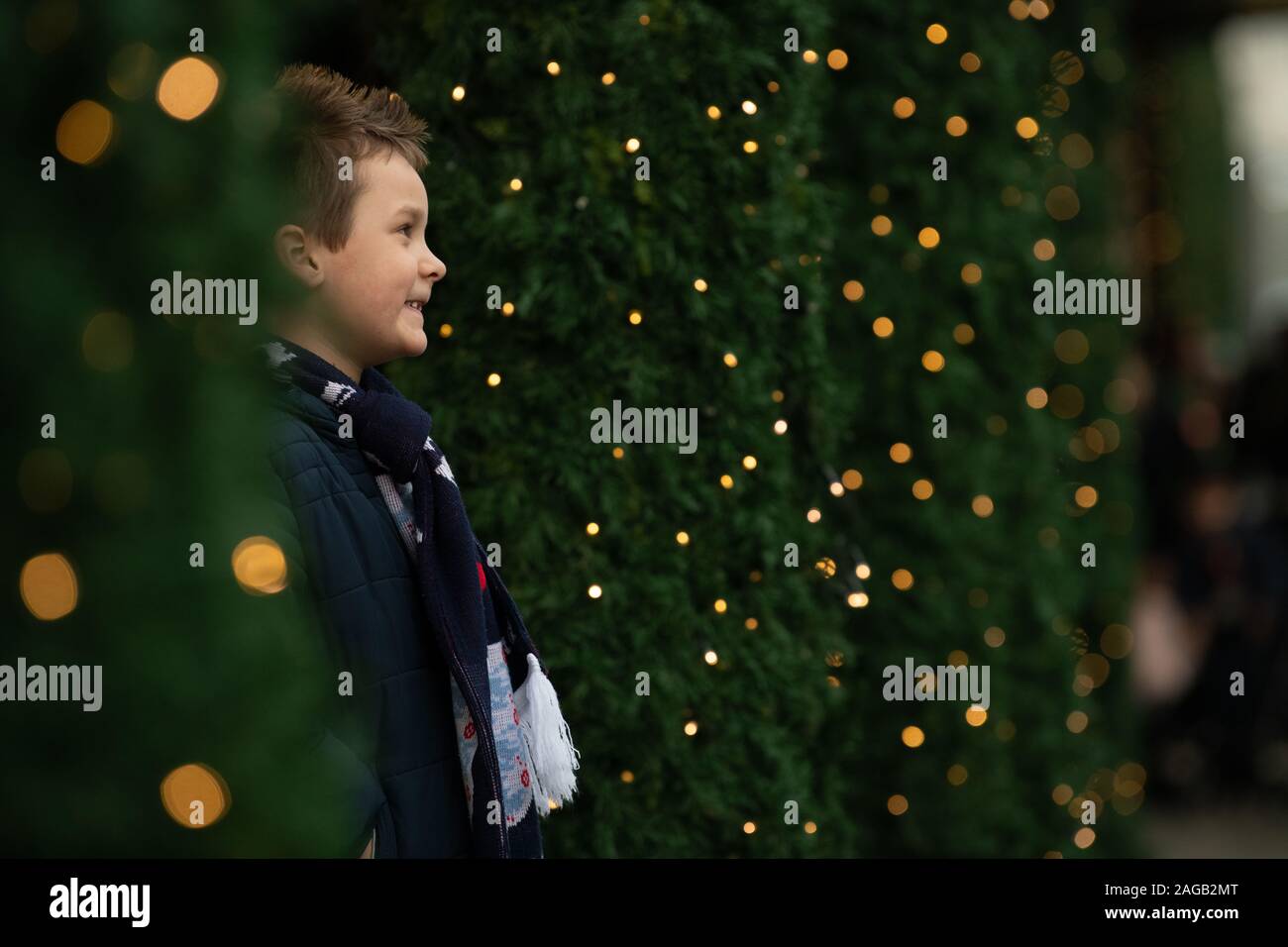 young boy posing between Christmas trees outside Selfridges Stock Photo