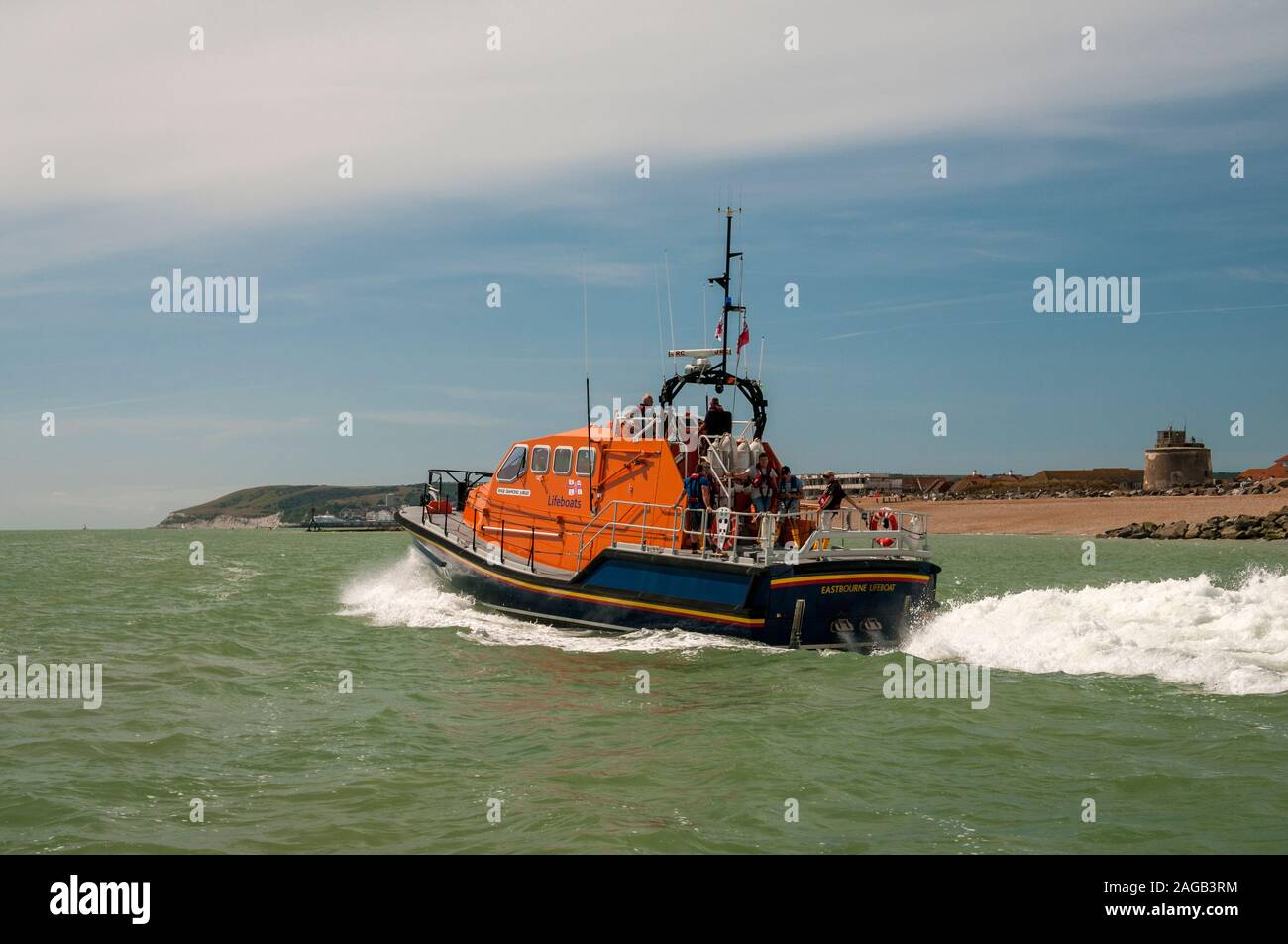 Eastbourne RNLI lifeboat with crew leaving Sovereign harbour with the Martello Tower in the background, Eastbourne, East Sussex, UK Stock Photo