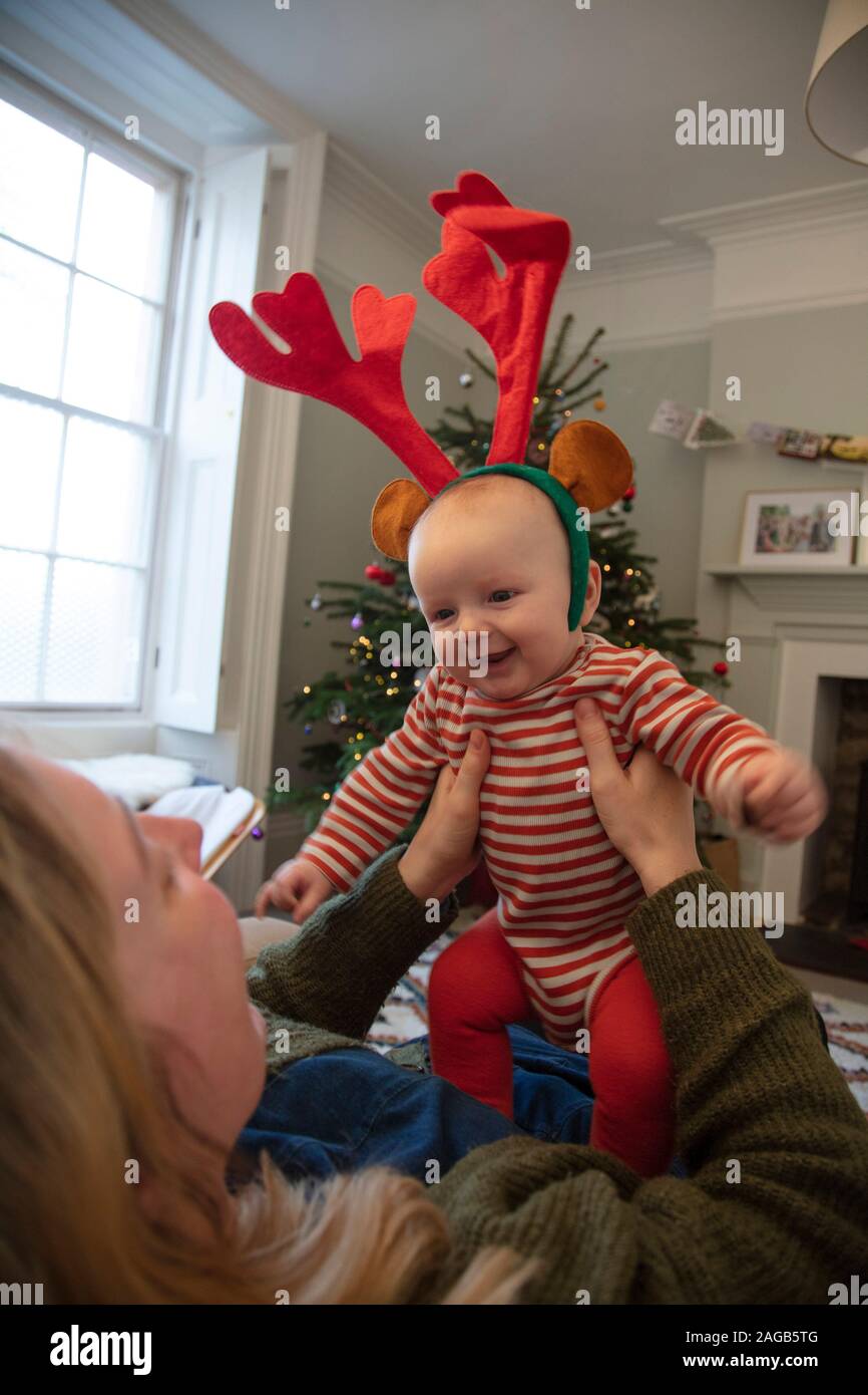 Cute baby wearing festive reindeer antlers playing with mum at christmas Stock Photo