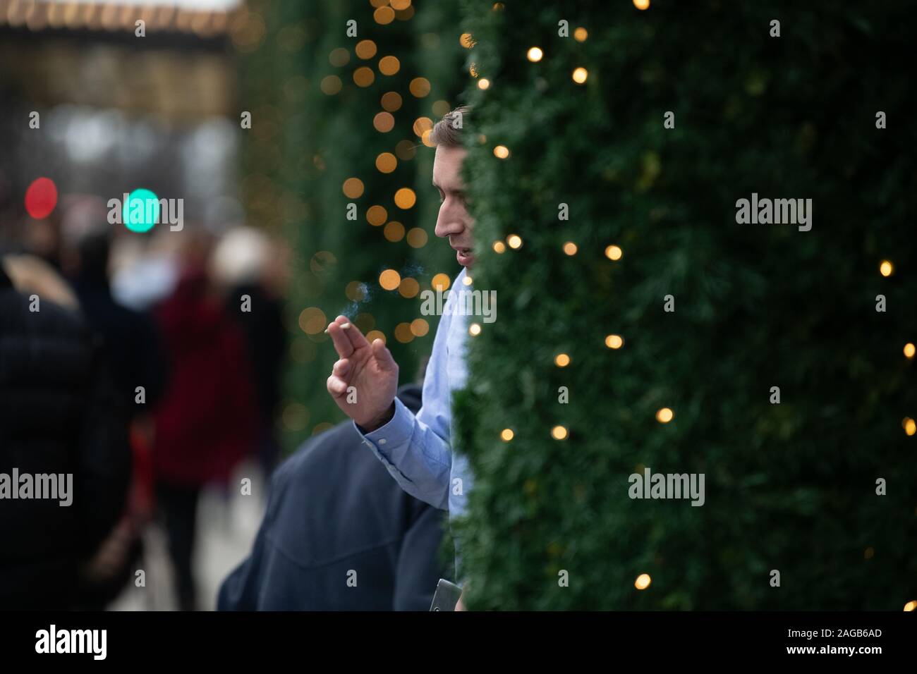Man smoking a cigarette between the Christmas Trees outside Selfridges