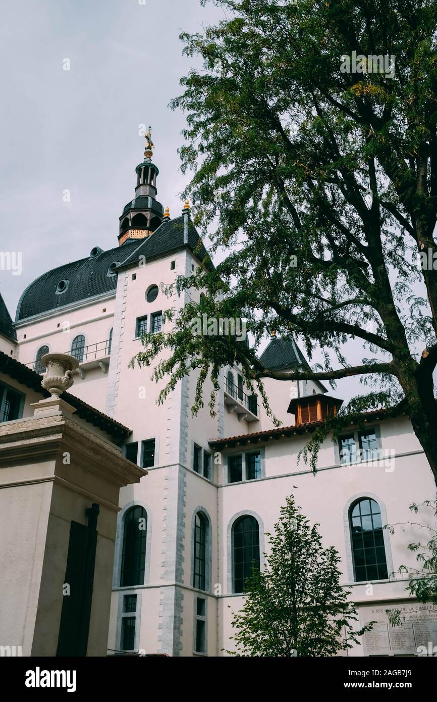 Vertical low angle shot of a cathedral next to a tree under the cloudy ...