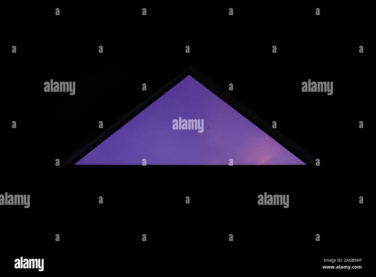 Closeup shot of a perfect triangle window looking at the mesmerizing purple sky Stock Photo