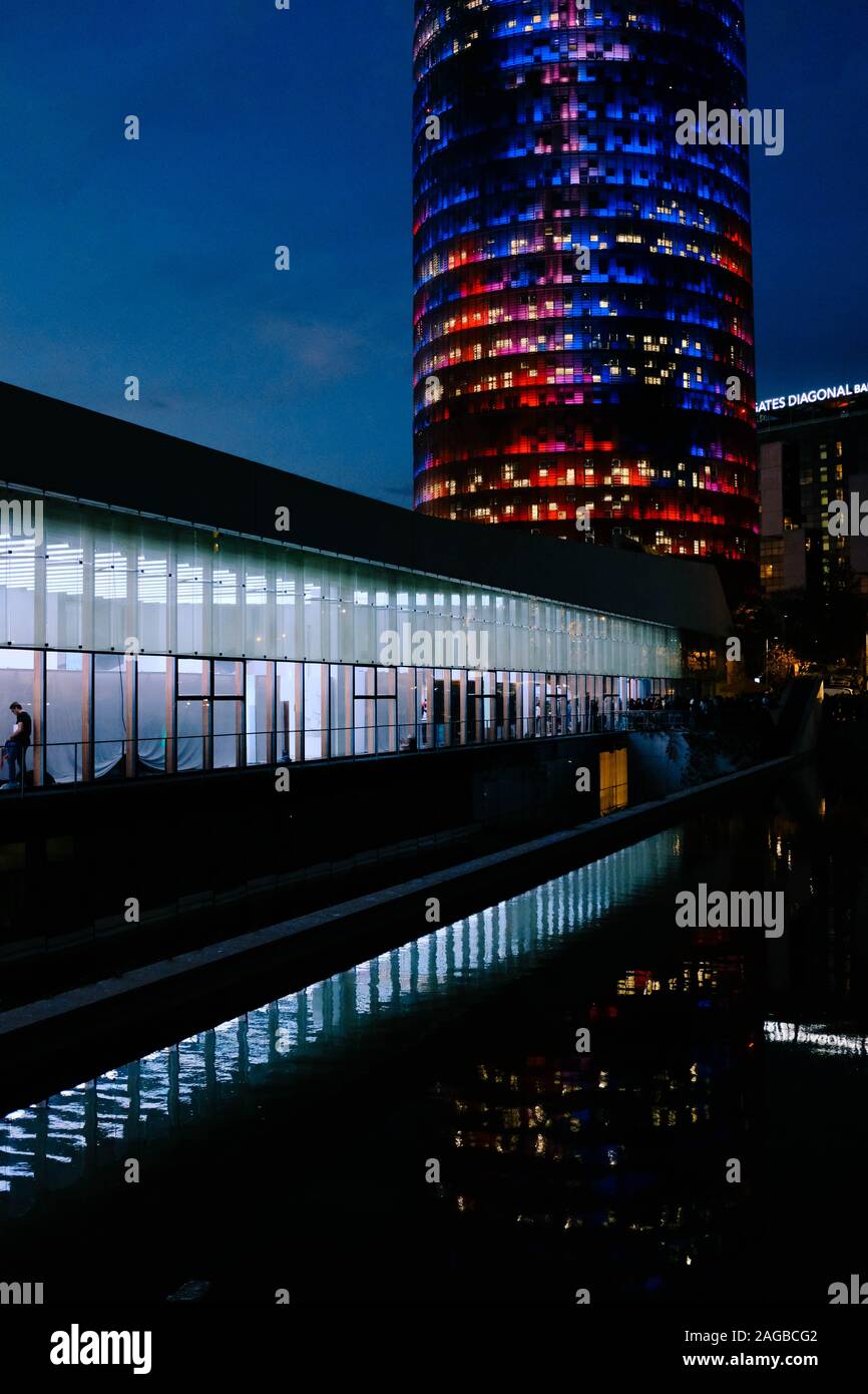 Vertical shot of a glass building and a tower with colorful lights captured at night Stock Photo