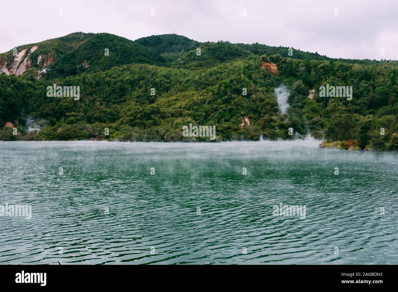 Steam coming out of a beautiful body of water surrounded by green mountains Stock Photo