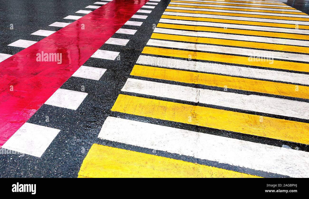 Pedestrian crossing with white and yellow stripes on the asphalt road ...