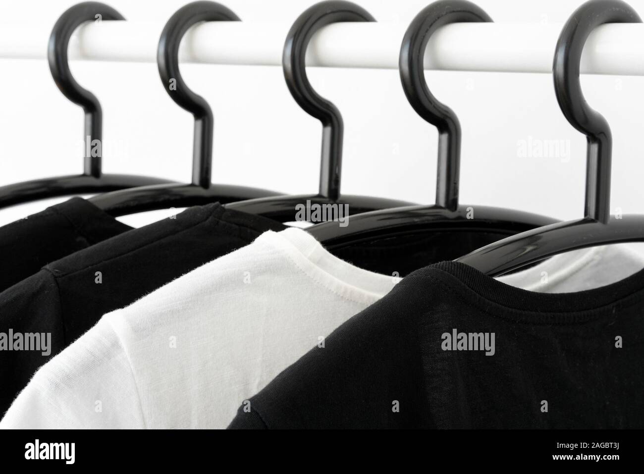 black and white color tone clothes on hangers in wardrobe. Woman minimalist wardrobe. Horizontal banner Stock Photo