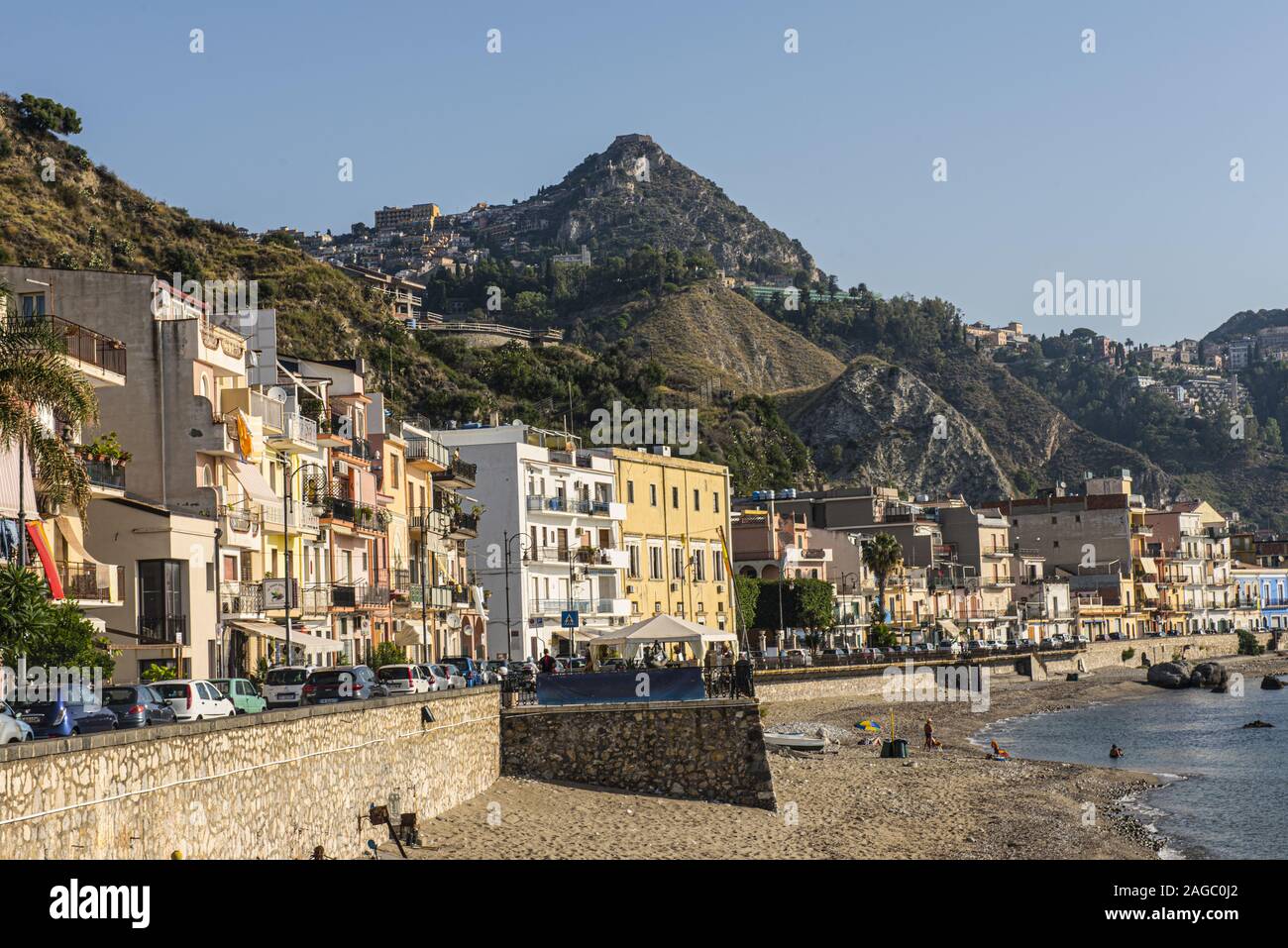View of Taormina from Naxos with buildings, sea, rocks and blue sky Stock Photo