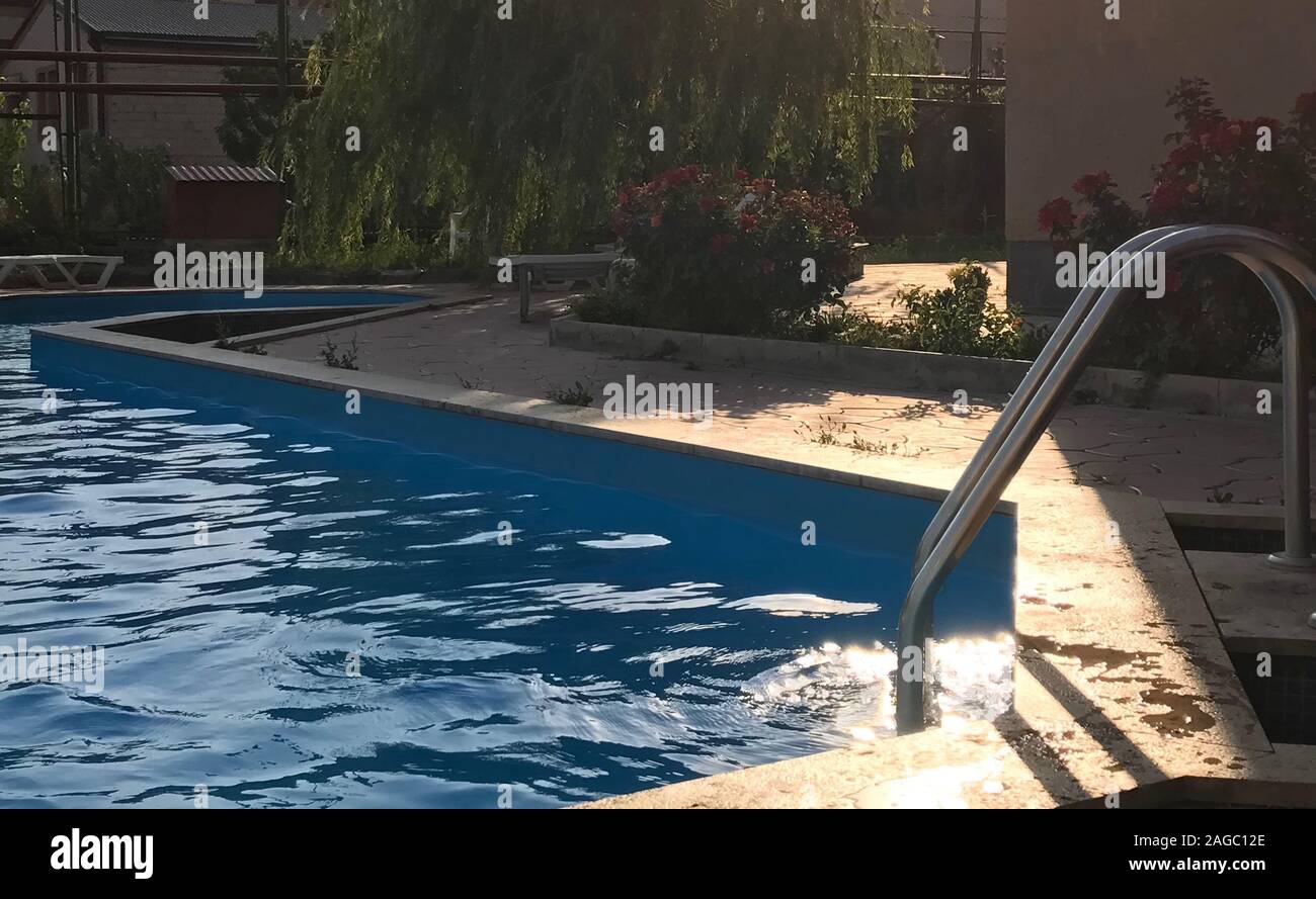 High angle shot of a pool in front of a house surrounded by beautiful garden flowers Stock Photo