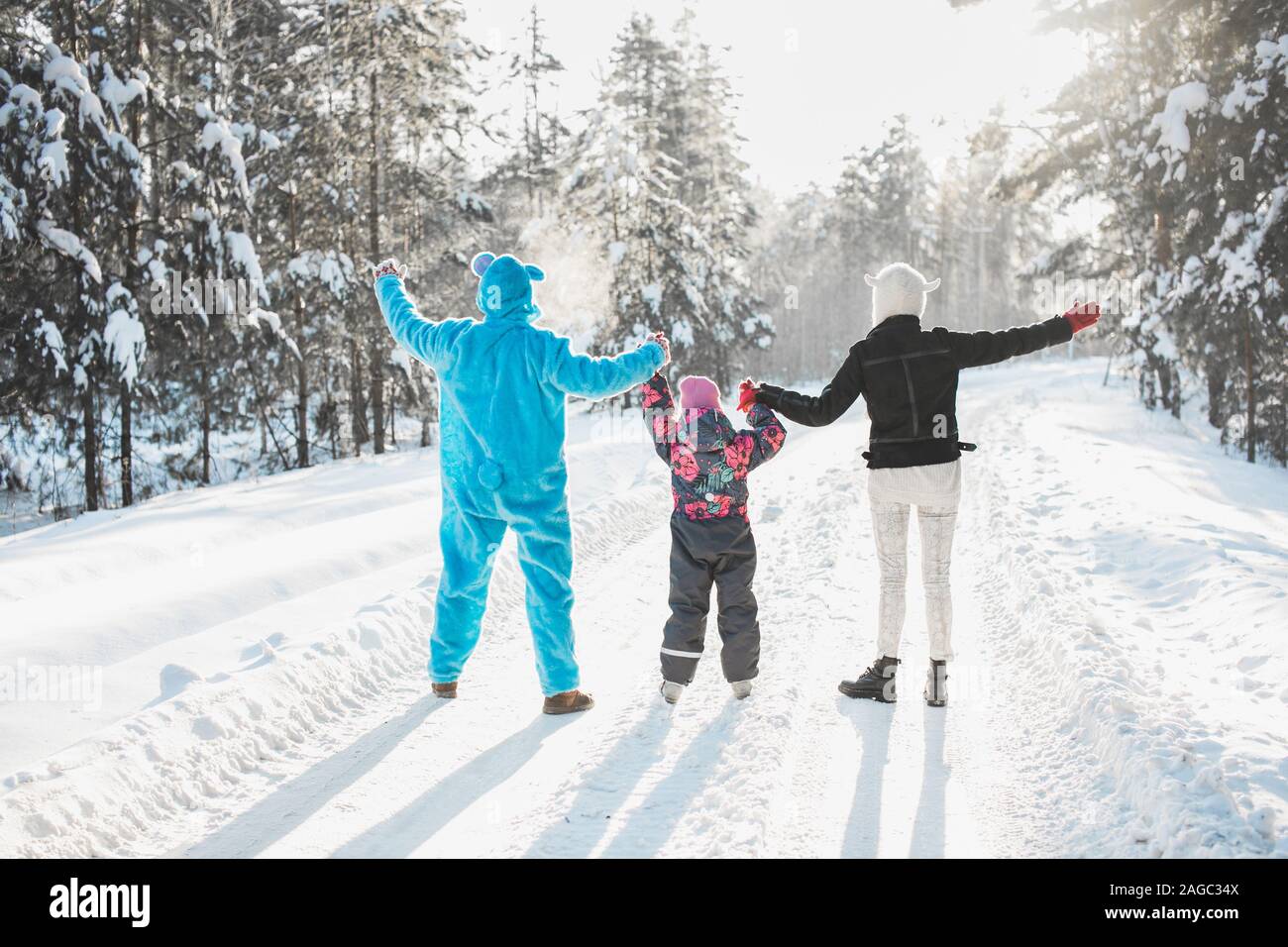 Beautiful shot of two people in cartoon costumes and a kid standing on a road in the snowy forest Stock Photo