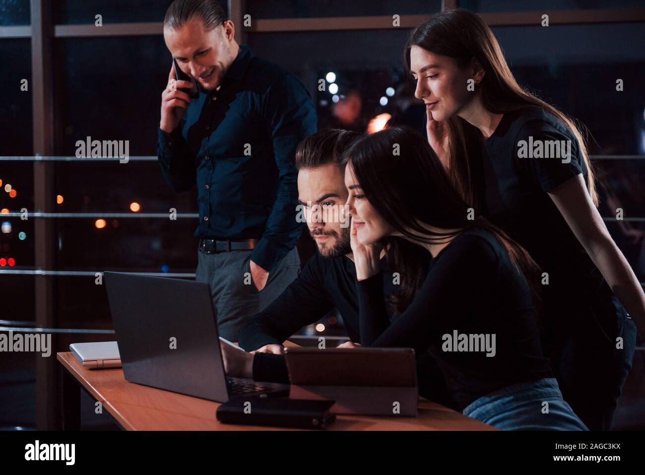 Just a bit and we will be on top. Team of young business people works on their project at night time in the office Stock Photo