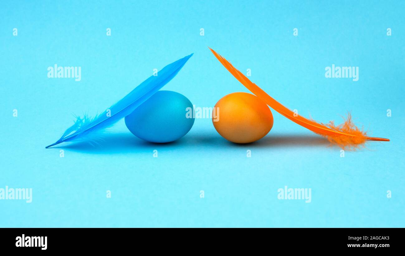 Easter multi-colored eggs and feathers on blue background. Stock Photo