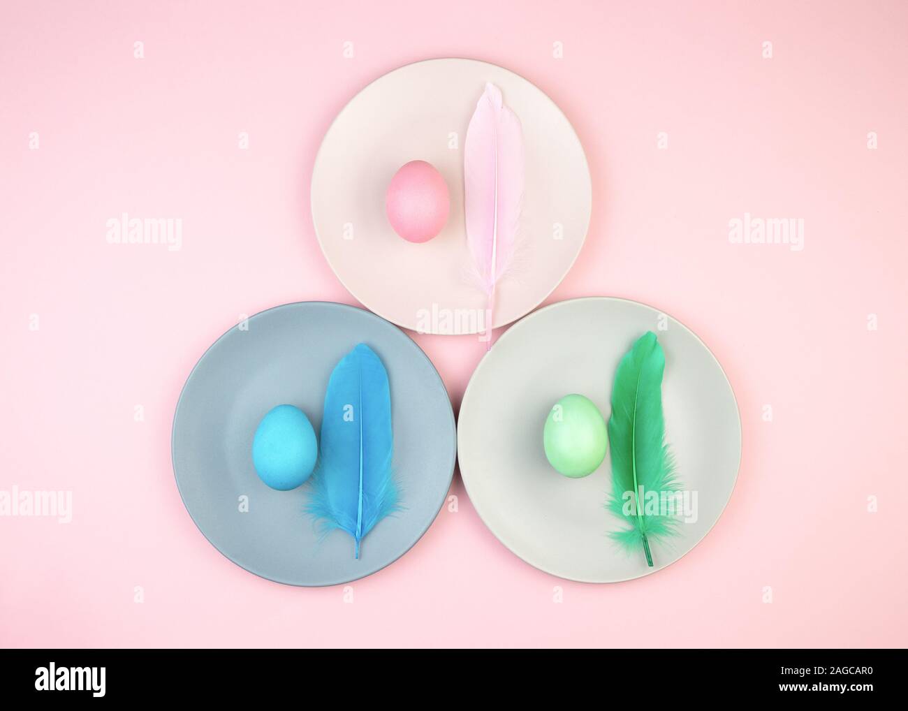 Easter multi-colored eggs and feathers on pink background. Stock Photo