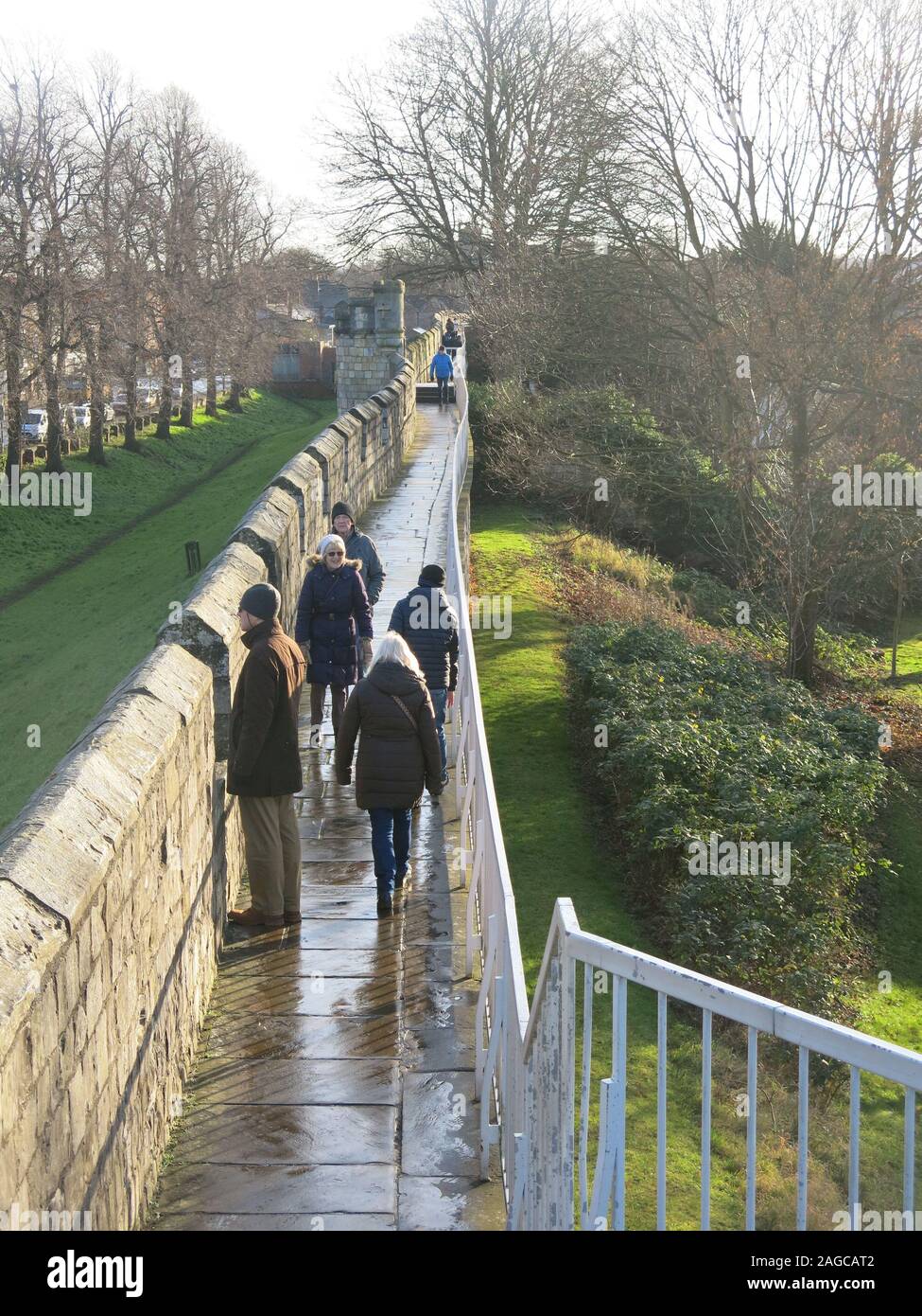 Pedestrians enjoying a walk along the northern section of the  city walls in York in the bright winter sunshine; December 2019. Stock Photo
