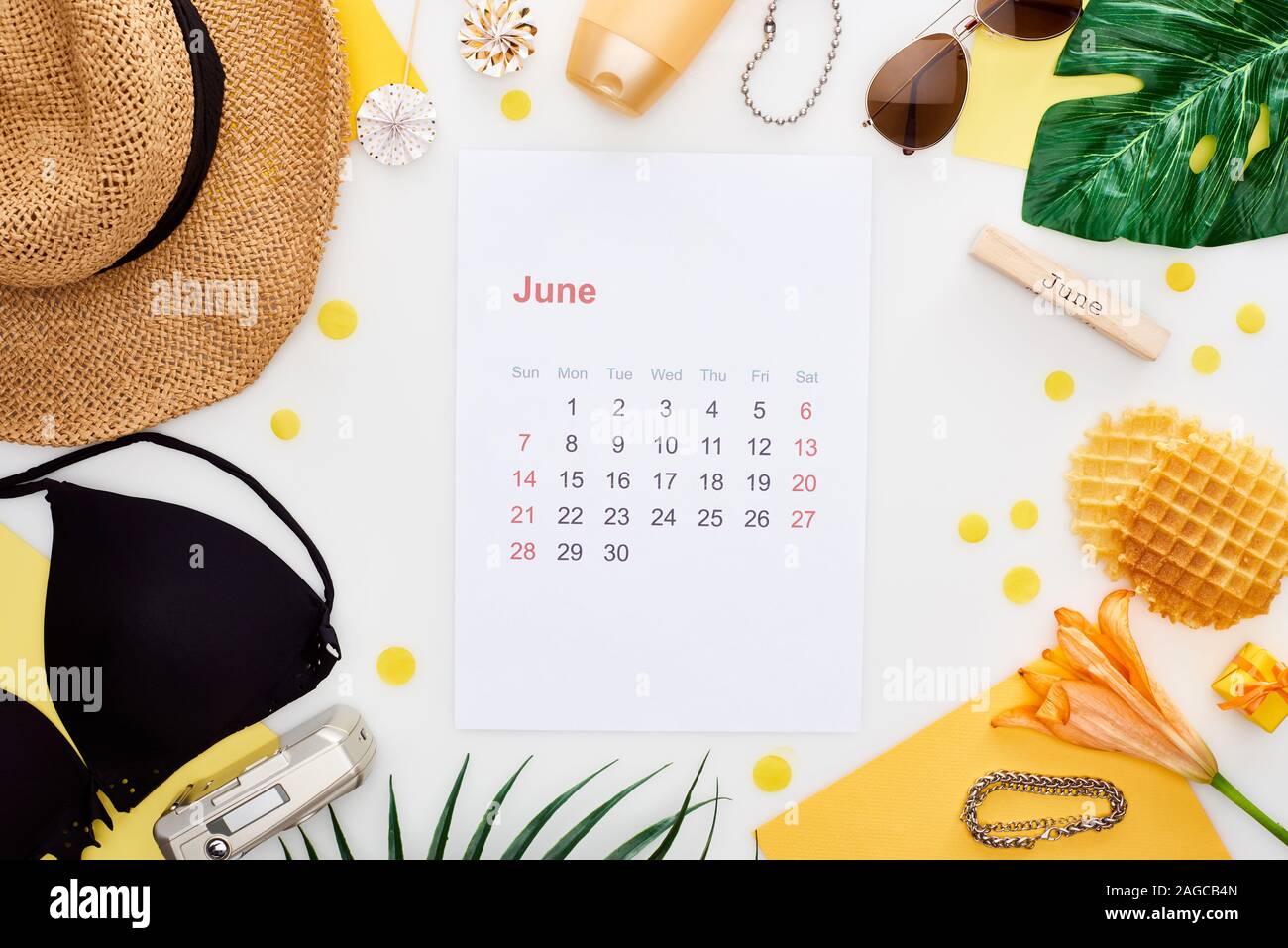 june calendar page, wooden block with june inscription, straw hat ...
