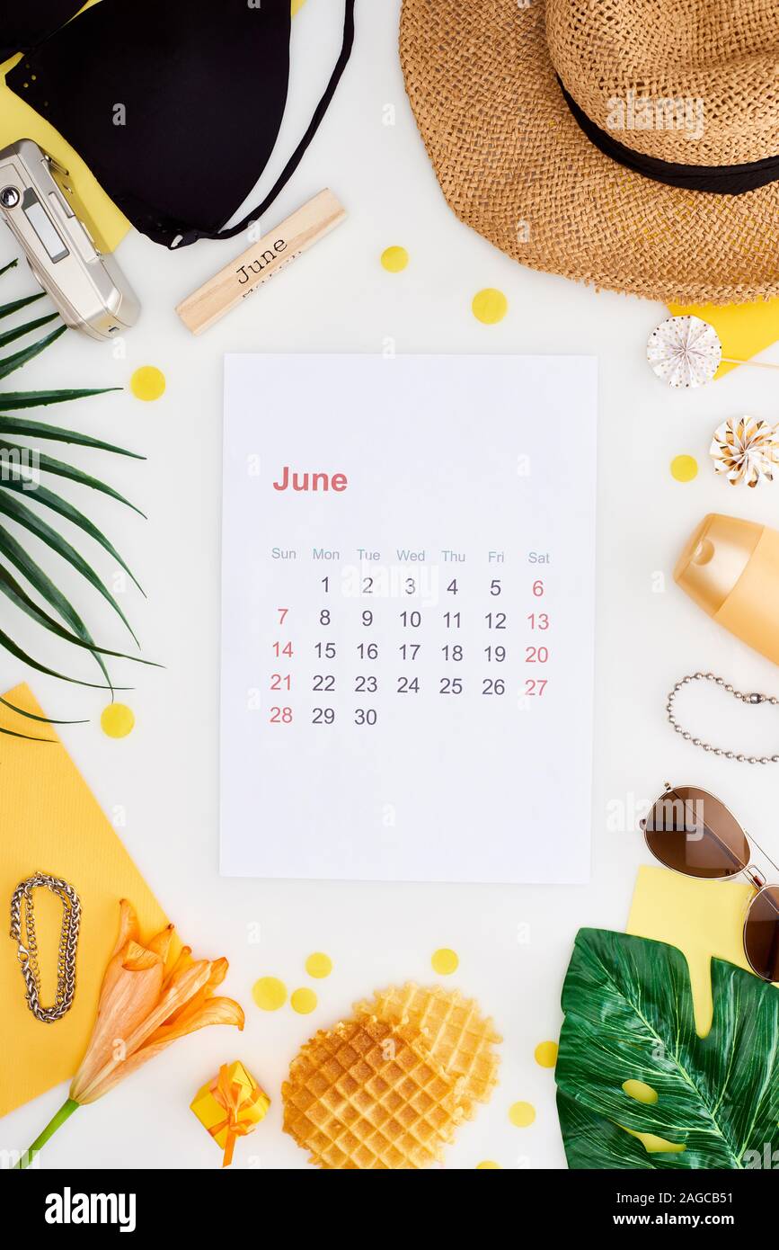 june calendar page, wooden block with june inscription, straw hat ...