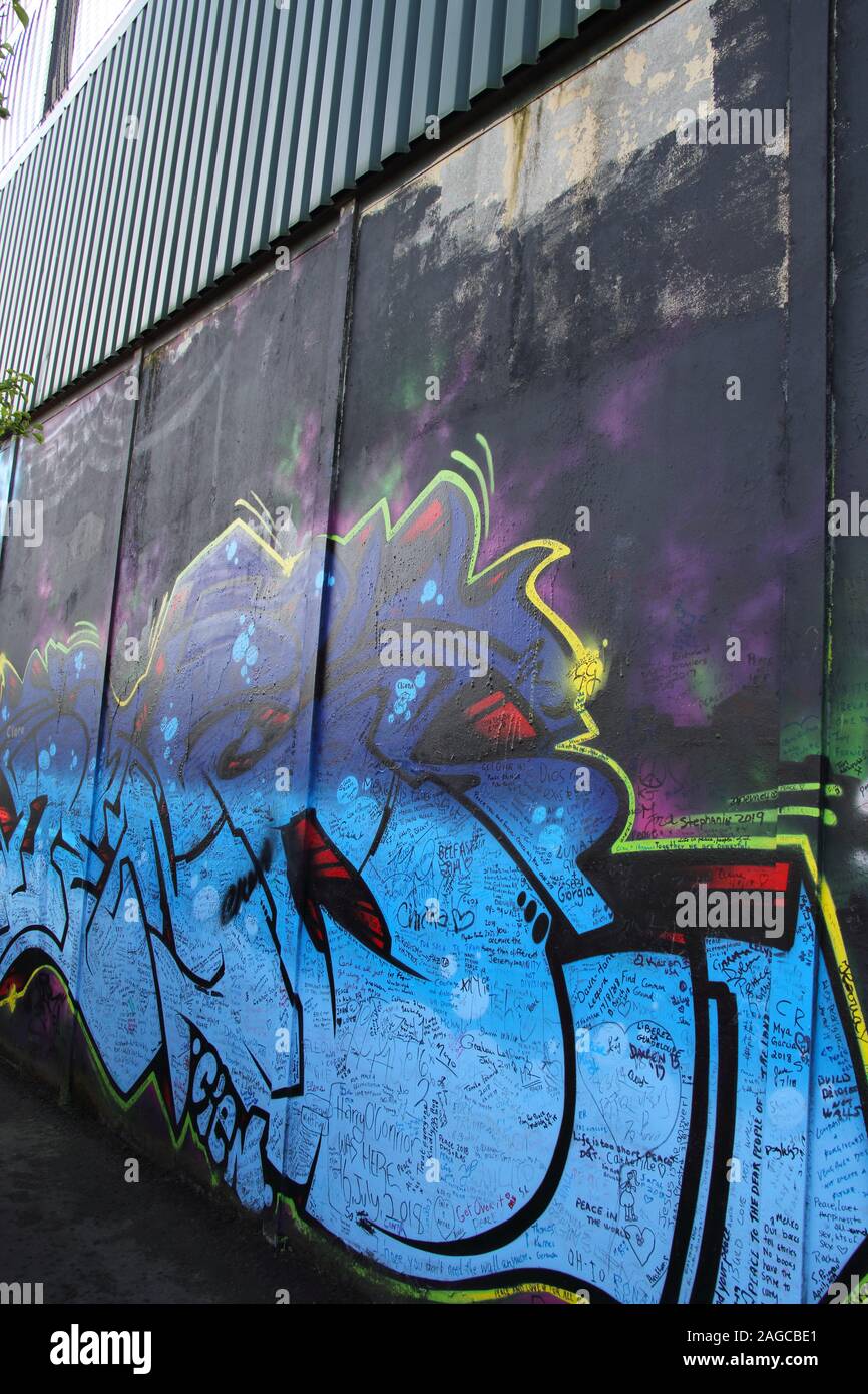 Colourful mural & graffiti on Peace wall,or Peace Line, running along Cupar Way in Belfast. It is one of the many separation barriers in N. Ireland Stock Photo