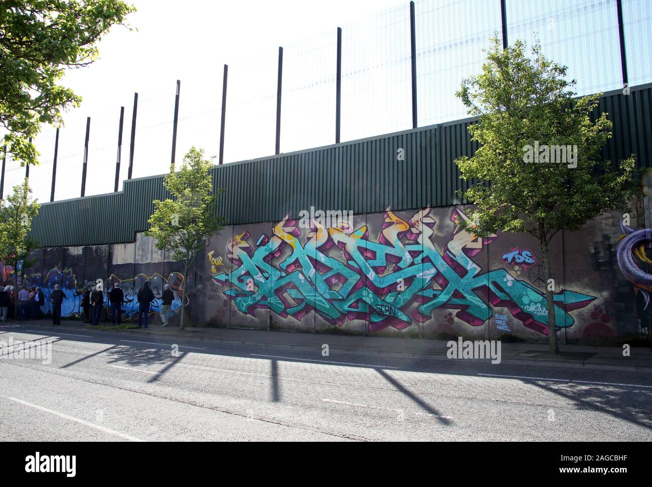 Tourists visiting colourful murals on Peace wall,or Peace Line, running along Cupar Way in Belfast. It is one of the separation barriers in Belfast. Stock Photo