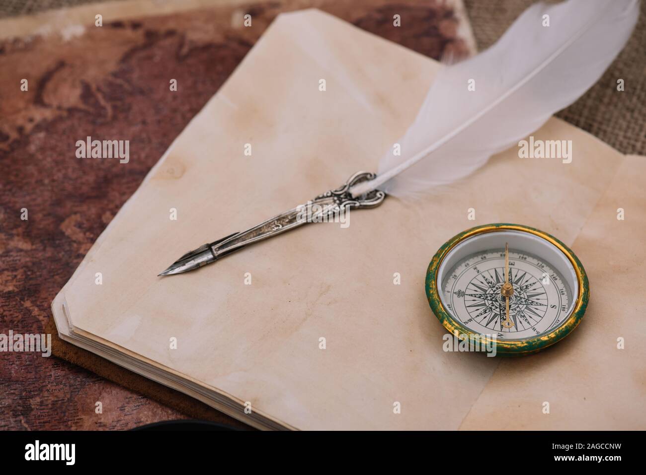 nib and compass on blank page of copy book on old world map Stock Photo