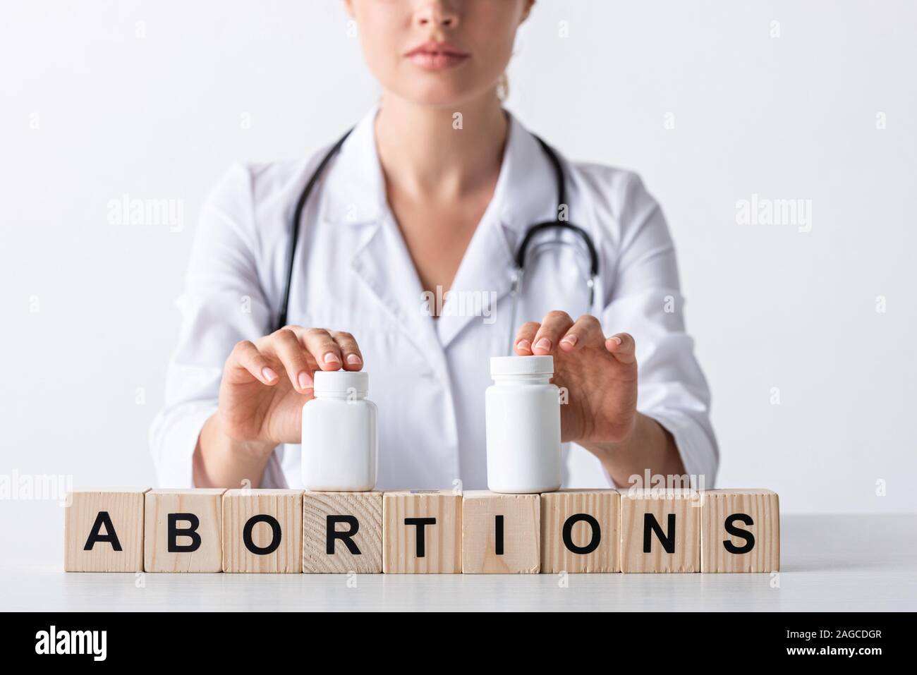 cropped view of doctor touching bottles on cubes with abortion letters Stock Photo