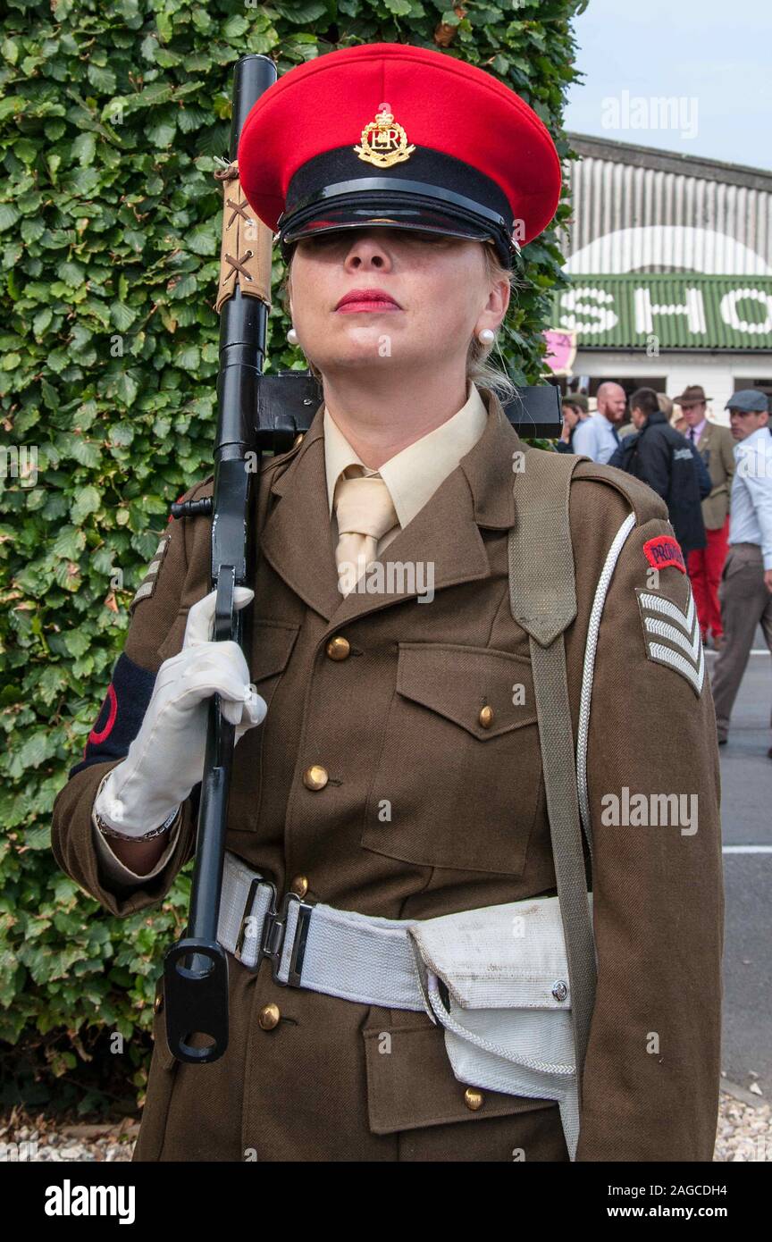 Female in Military Police uniform costume at the Goodwood Revival, West Sussex, UK. Mean, stern appearance with gun. Means business Stock Photo
