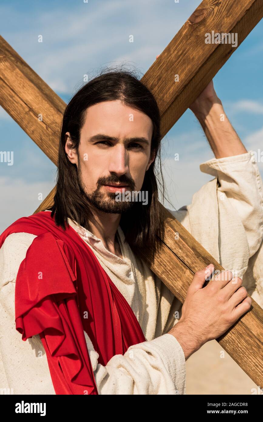 bearded jesus holding wooden cross and looking at camera Stock Photo ...
