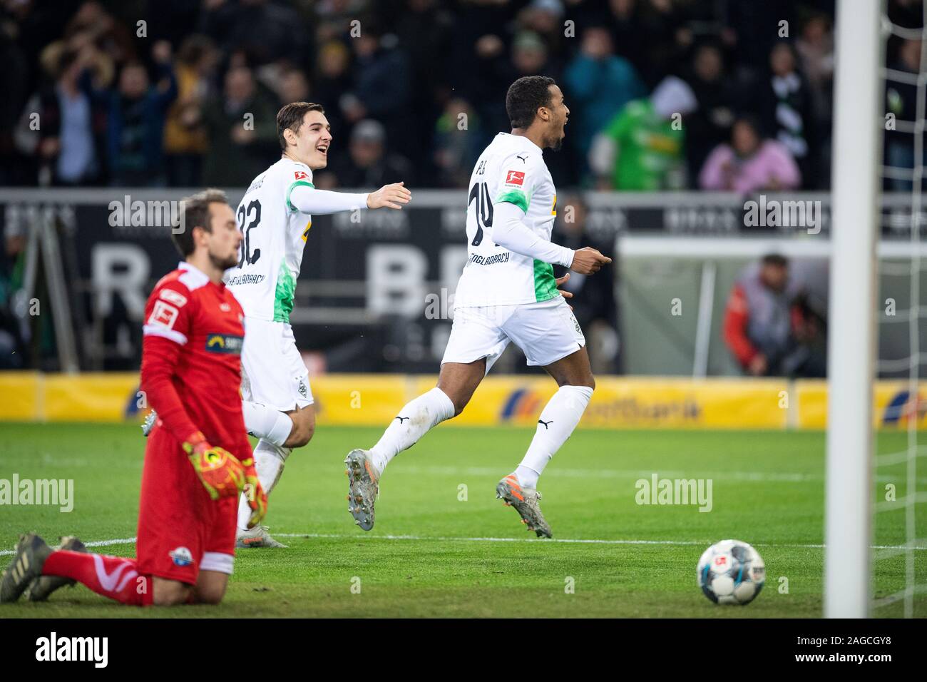 18 December 2019, North Rhine-Westphalia, Mönchengladbach: Soccer: Bundesliga, Borussia Mönchengladbach - SC Paderborn 07, 16th matchday in Borussia-Park. Gladbach's scorers Alassane Plea (r) and Florian Neuhaus (M) cheer for a 1-0 lead after the goal. On the left Paderborn's goalkeeper Leopold Zingerle. Photo: Marius Becker/dpa - IMPORTANT NOTE: In accordance with the requirements of the DFL Deutsche Fußball Liga or the DFB Deutscher Fußball-Bund, it is prohibited to use or have used photographs taken in the stadium and/or the match in the form of sequence images and/or video-like photo seque Stock Photo