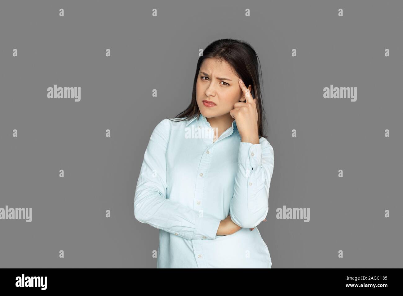 Freestyle. Young woman standing isolated on grey scratching face concerned Stock Photo