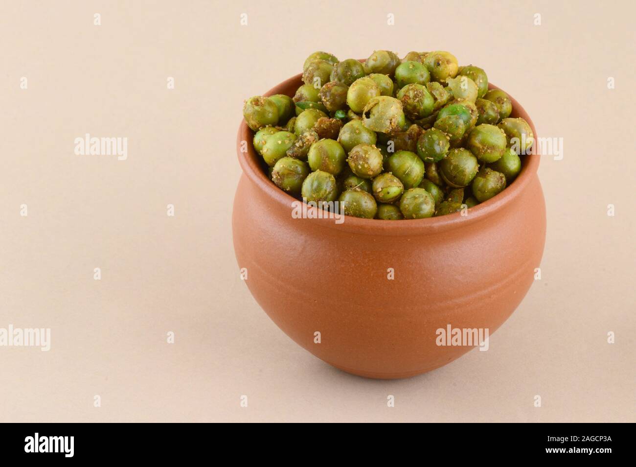 Spiced fried green peas {chatpata matar} Indian snack. Dried salted green peas in clay pot Stock