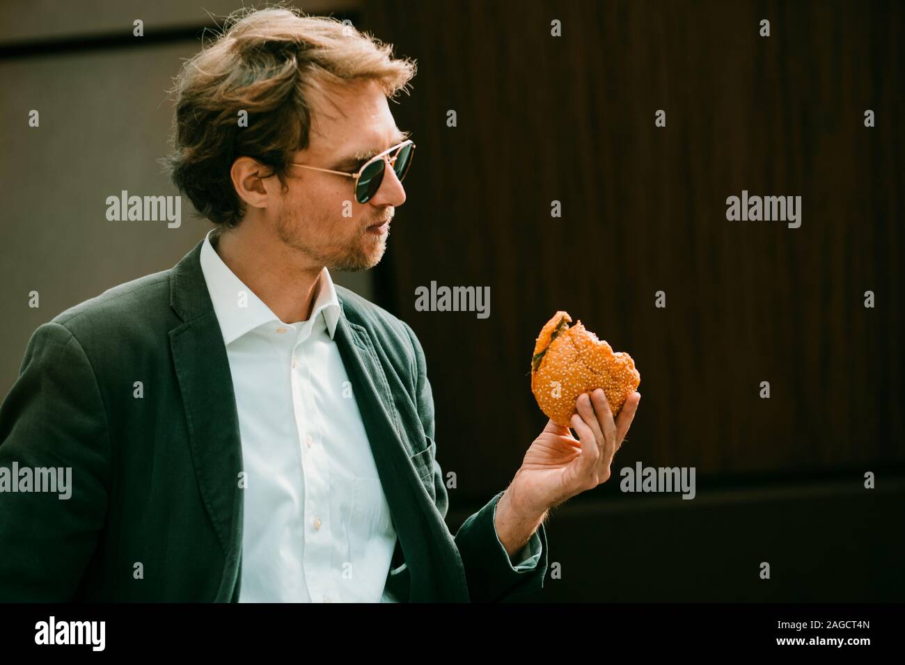 Man Holding A Burger In His Hand Stock Photo