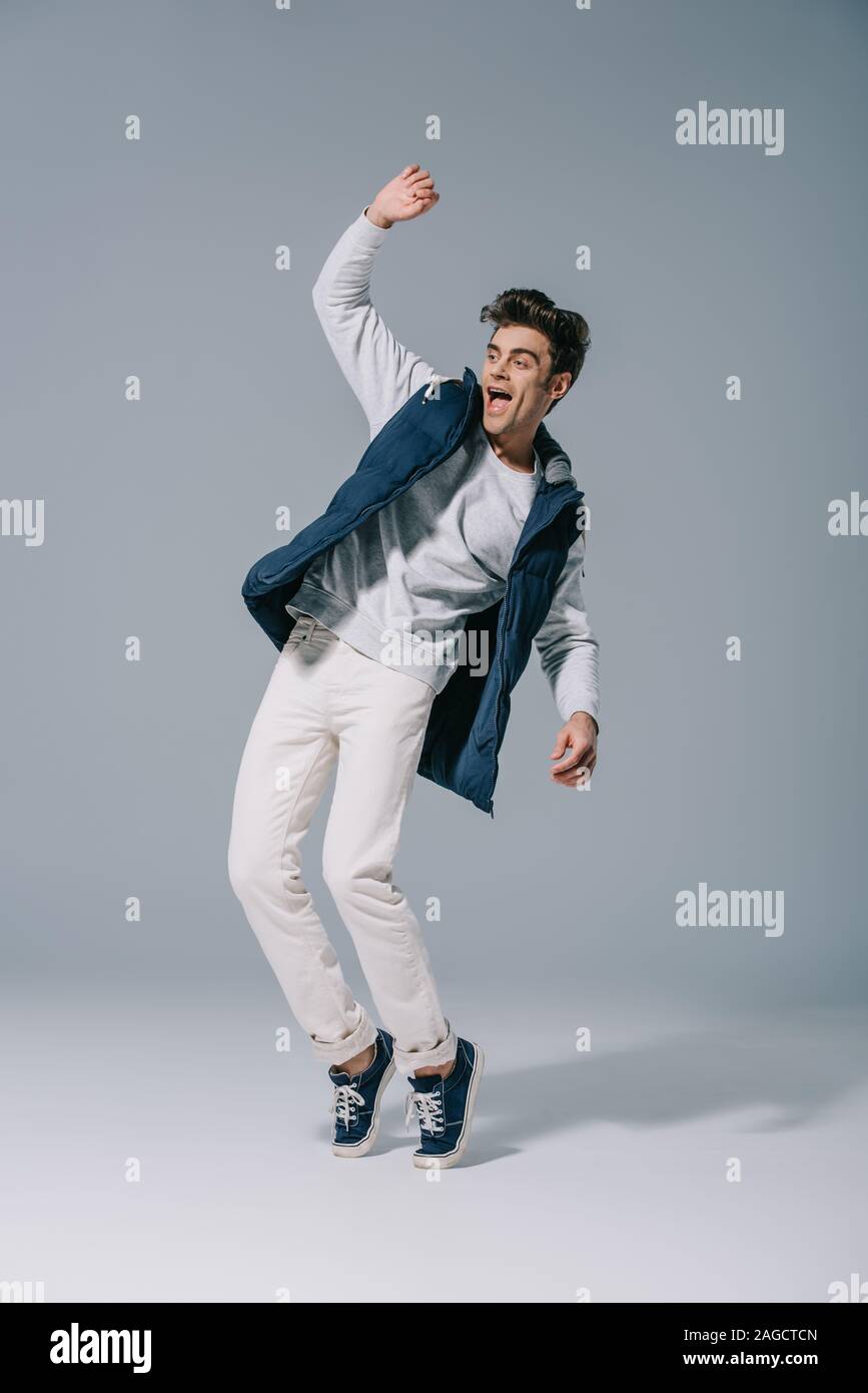 handsome excited man jumping in autumn waistcoat on grey Stock Photo