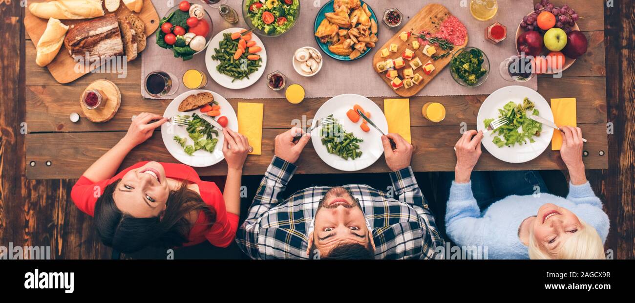 Family eating food behind table, looking up Stock Photo - Alamy