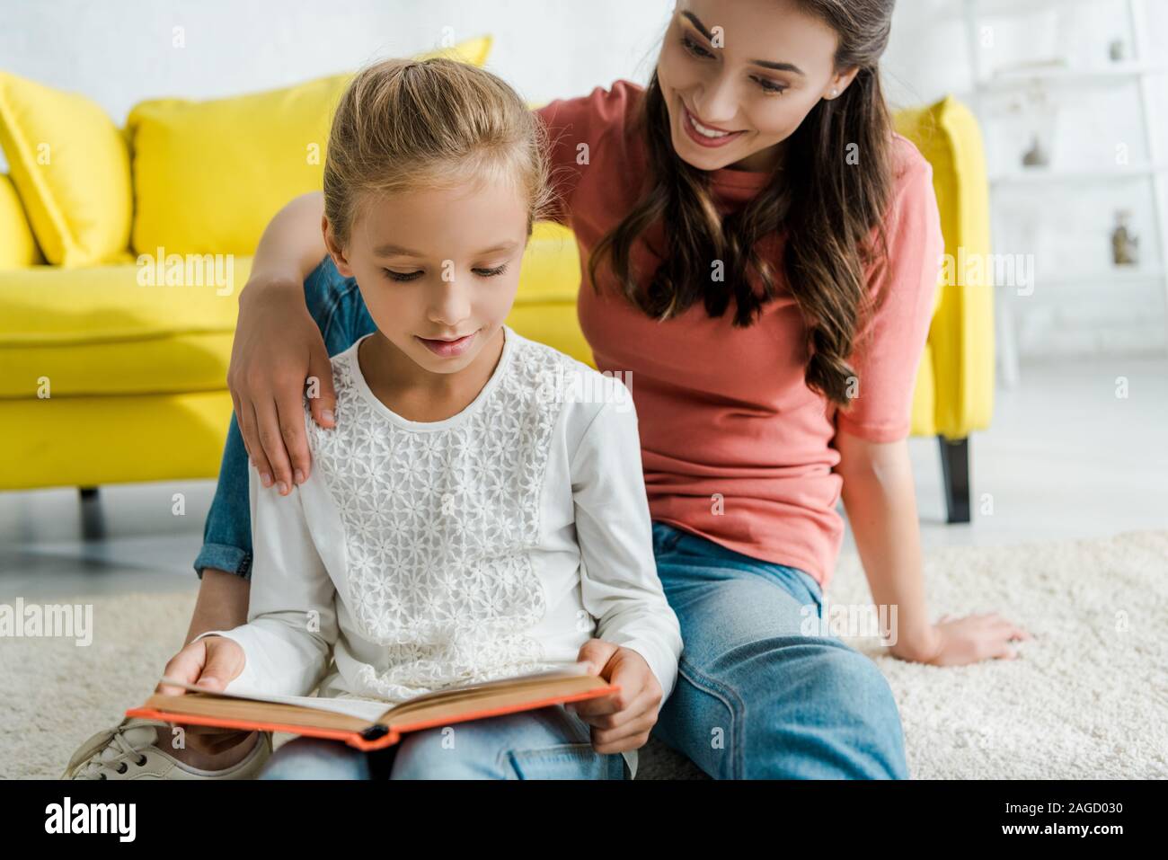 happy babysitter sitting with cute kid reading book Stock Photo - Alamy