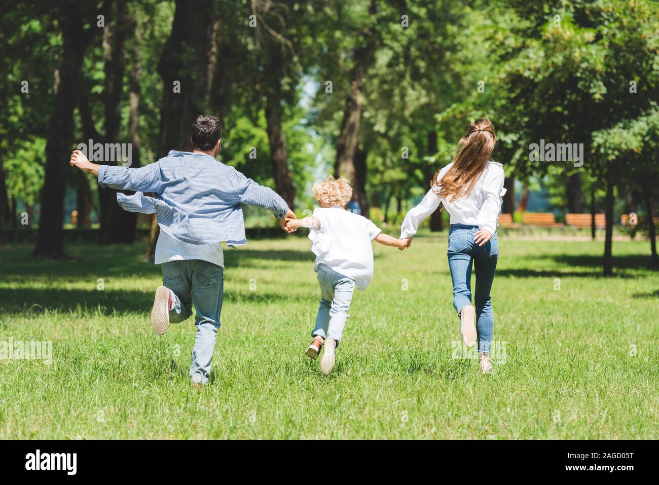 happy family holding hands and running in park during daytime Stock ...