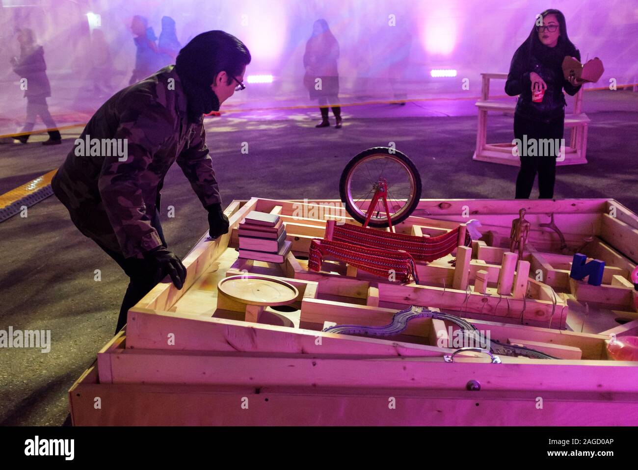Participants play with a larger-than-life labyrinth tilting maze game at the nighttime Nuit Blanche public art events in Winnipeg, Manitoba Stock Photo