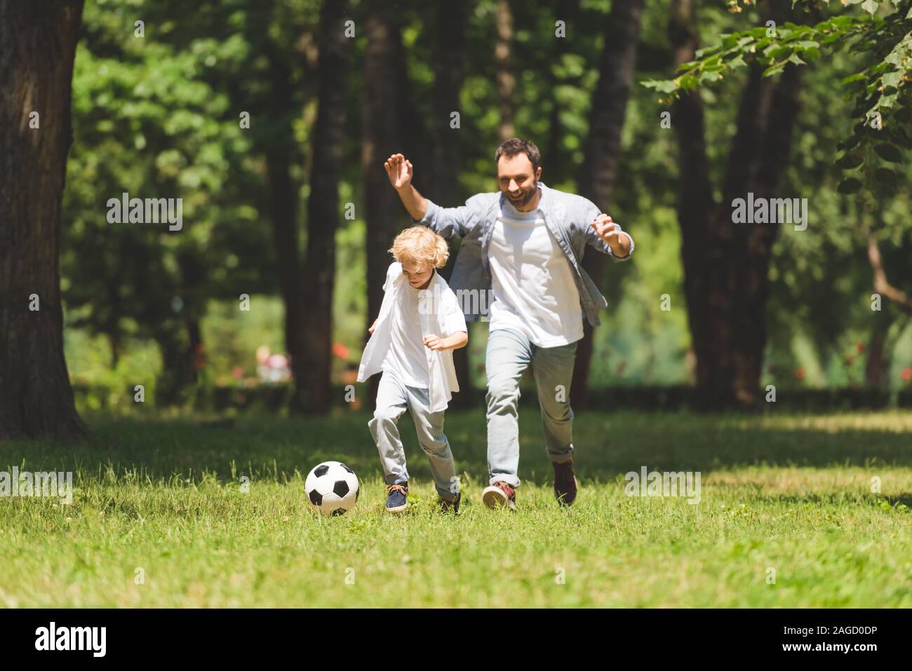 handsome father and adorable son playing football in park Stock Photo ...