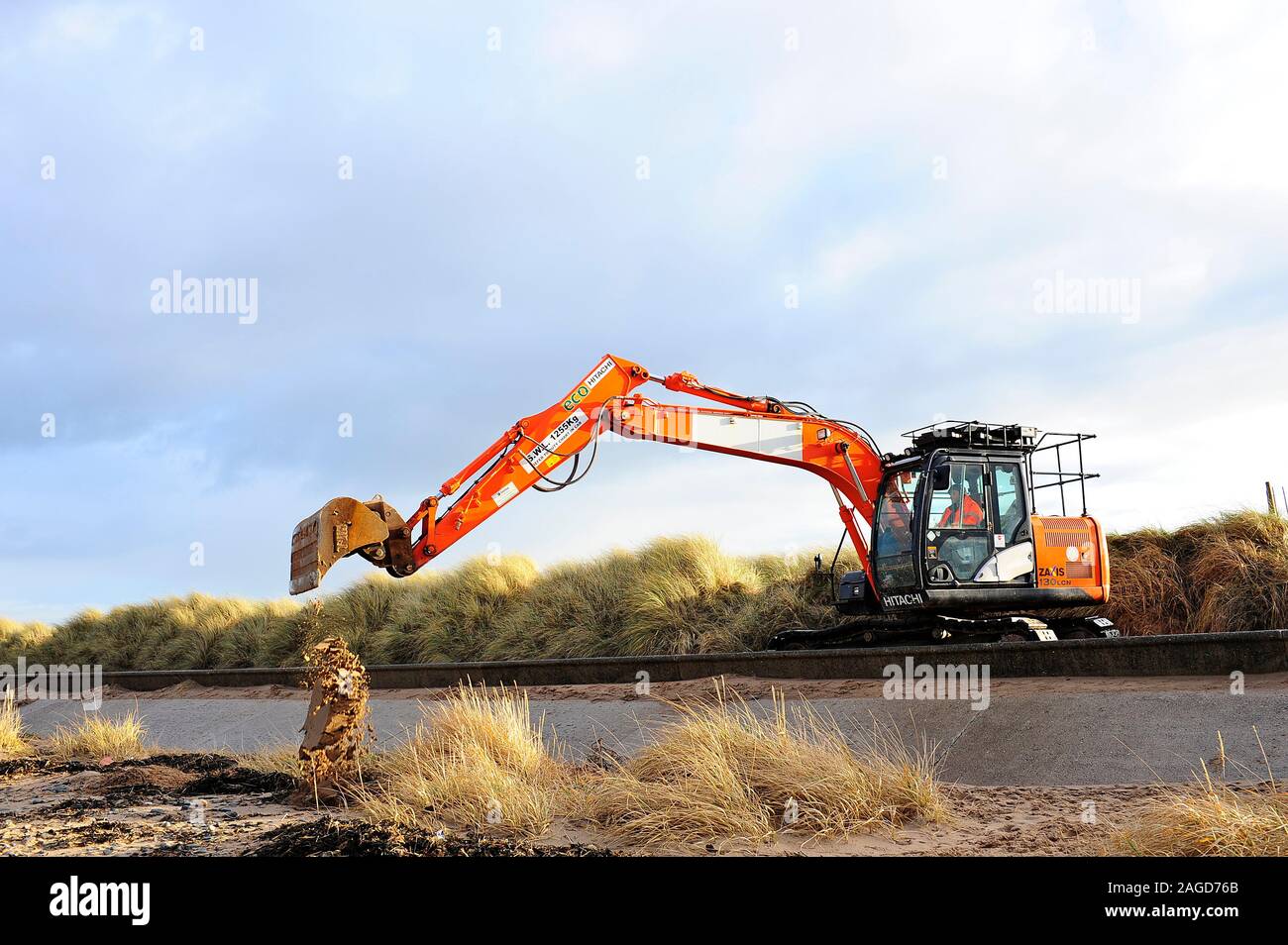 Excavator returning sand to the beach after gale force winds and storms at Fleetwood,UK Stock Photo