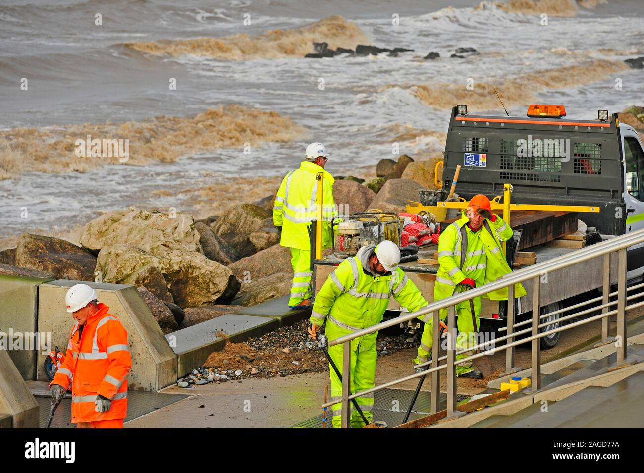 Workers in protective gear cleaning up after severe sea storm at Rossall,Fleetwood,UK Stock Photo
