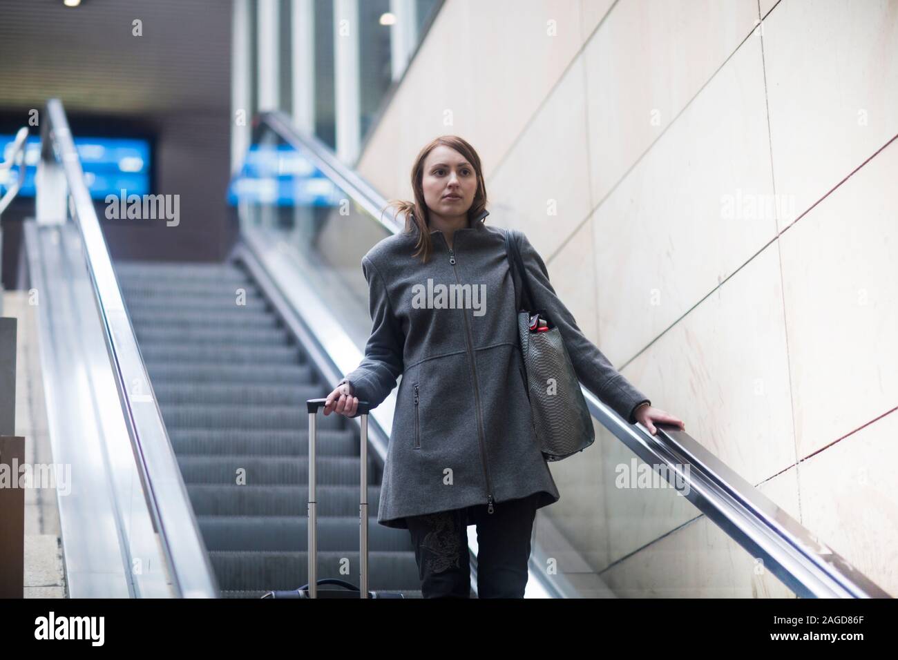 Young woman on escalator in train terminal Stock Photo