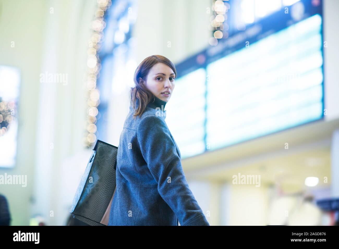 Young woman in front of digital board in train terminal Stock Photo
