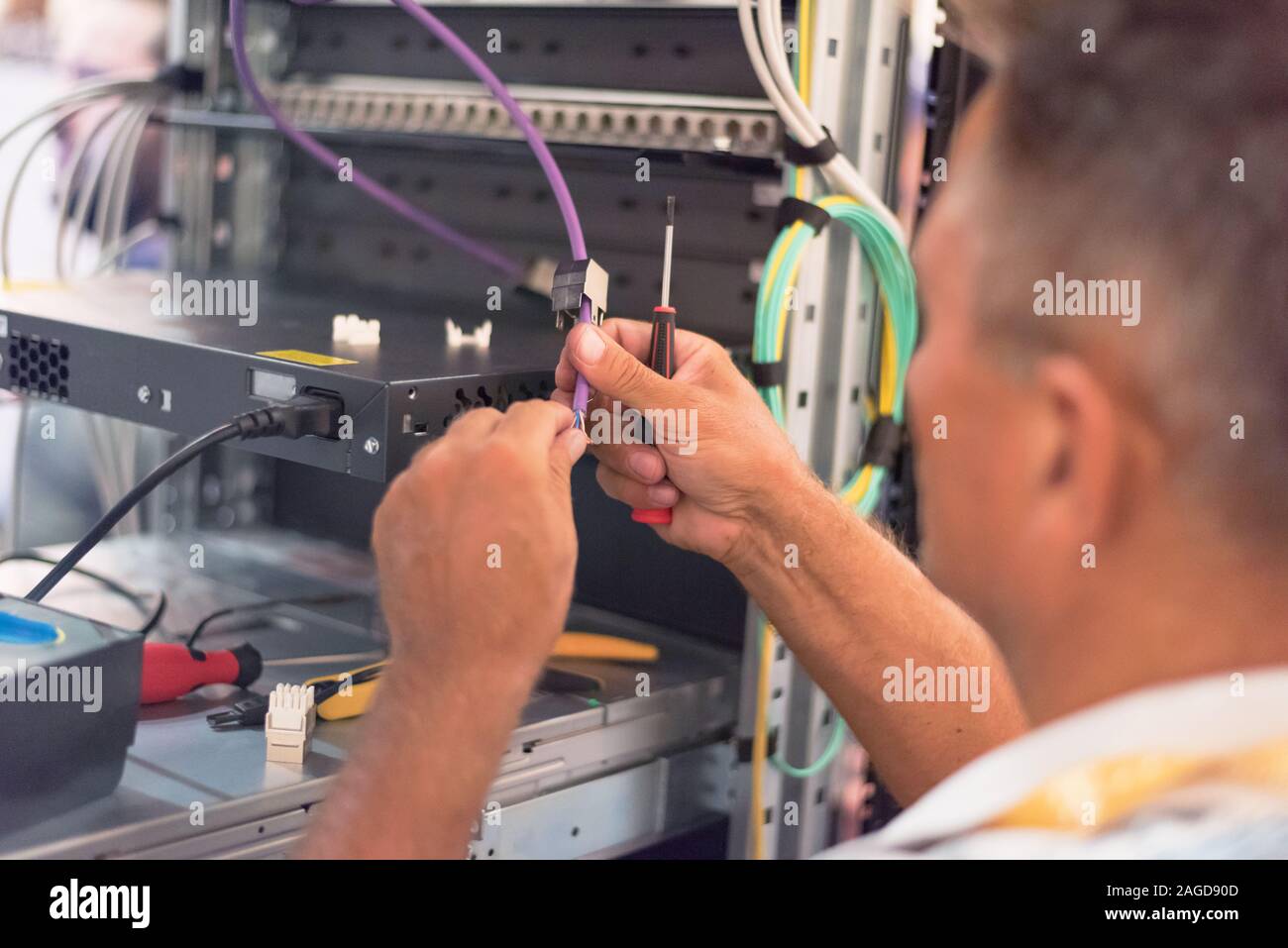 Rack Mounted Servers In A Server Room, man work with lan or network cables. Stock Photo