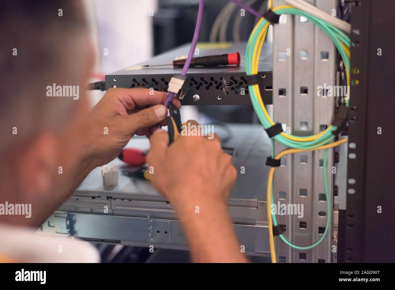 Rack Mounted Servers In A Server Room, man work with lan or network cables. Stock Photo