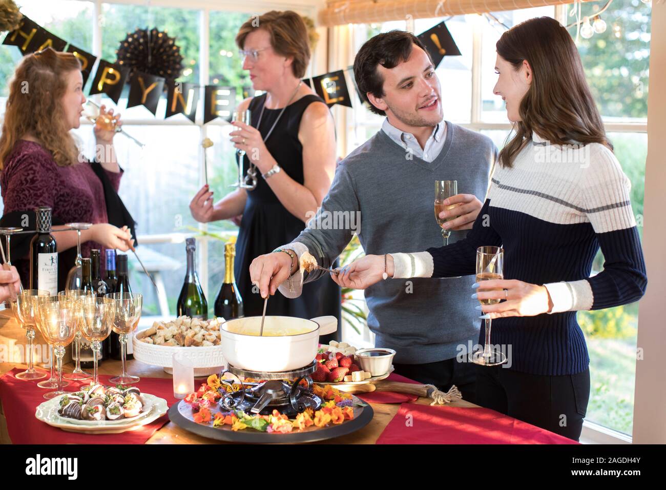young couple dipping bread in cheese fondue at a holiday fondue party Stock Photo