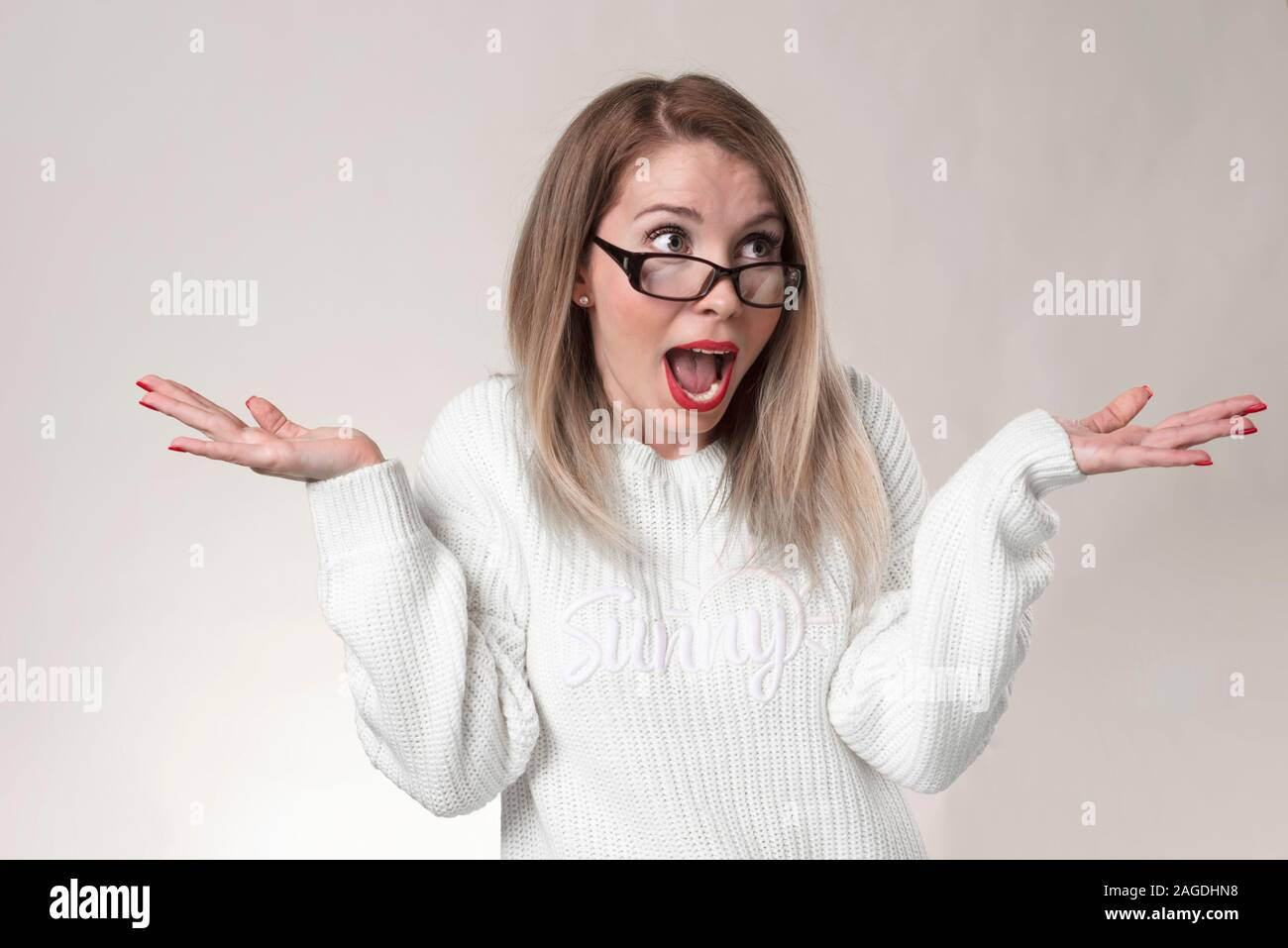 Portrait of young casual girl shrugging shoulders isolated over white background feeling confused while refusing to go out on date with guy she doesn Stock Photo
