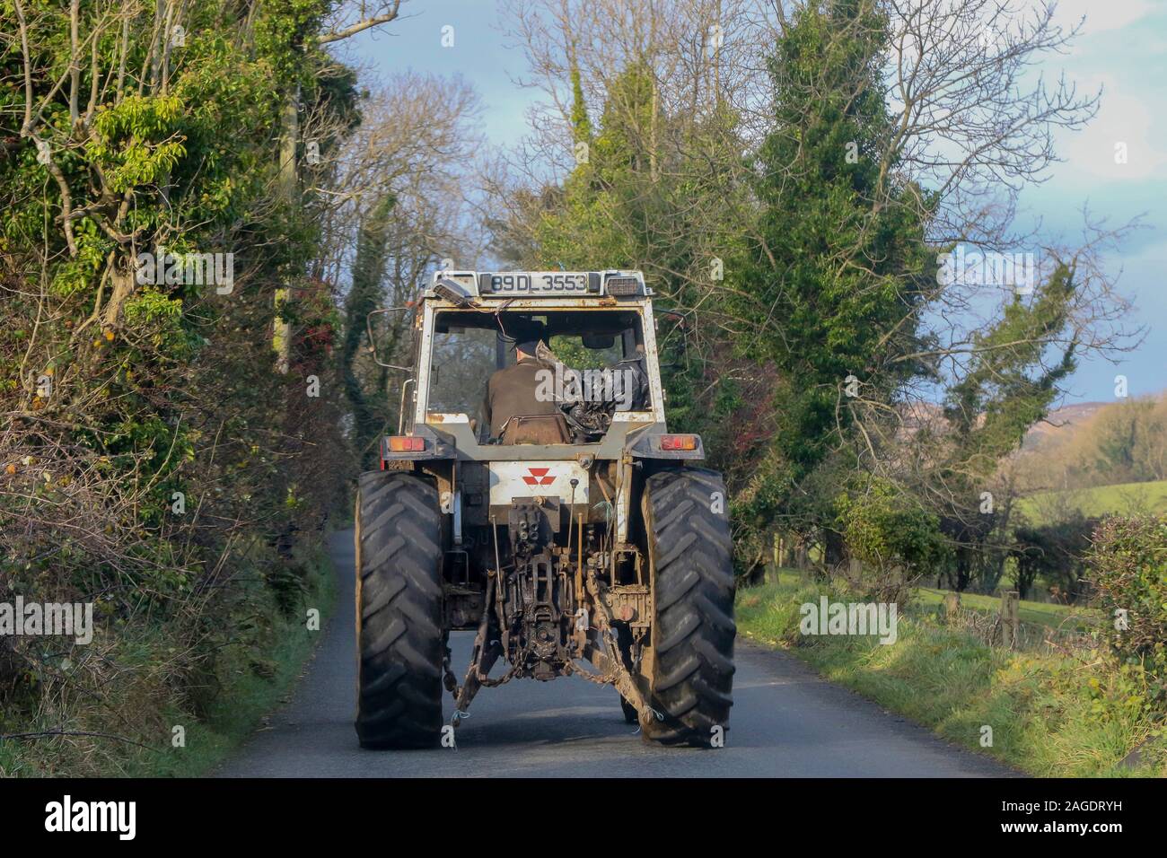 Farmer driving tractor in Ireland. An old white tractor on a country