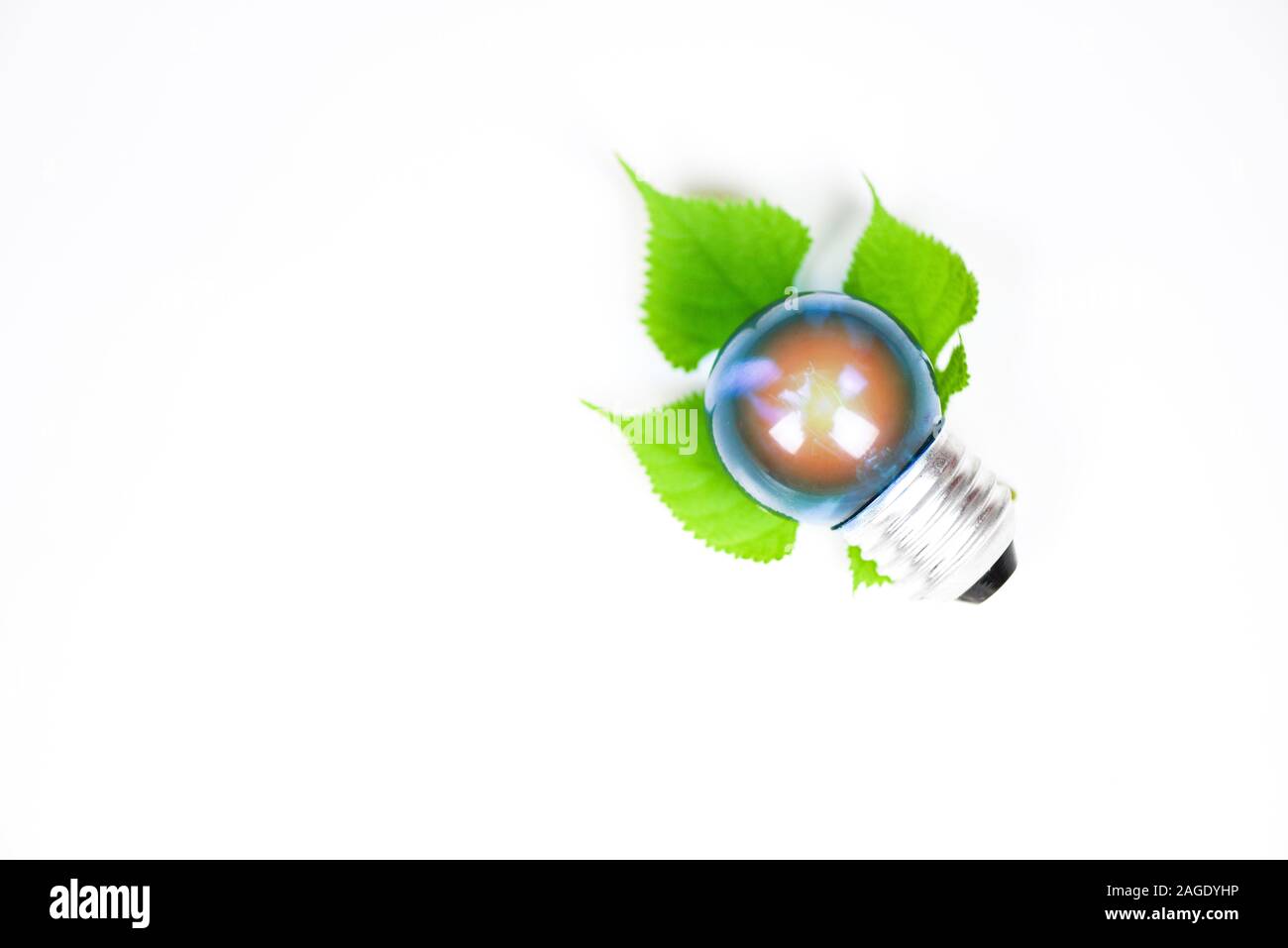 light bulb with light from the lamp with green leaf on white background ...