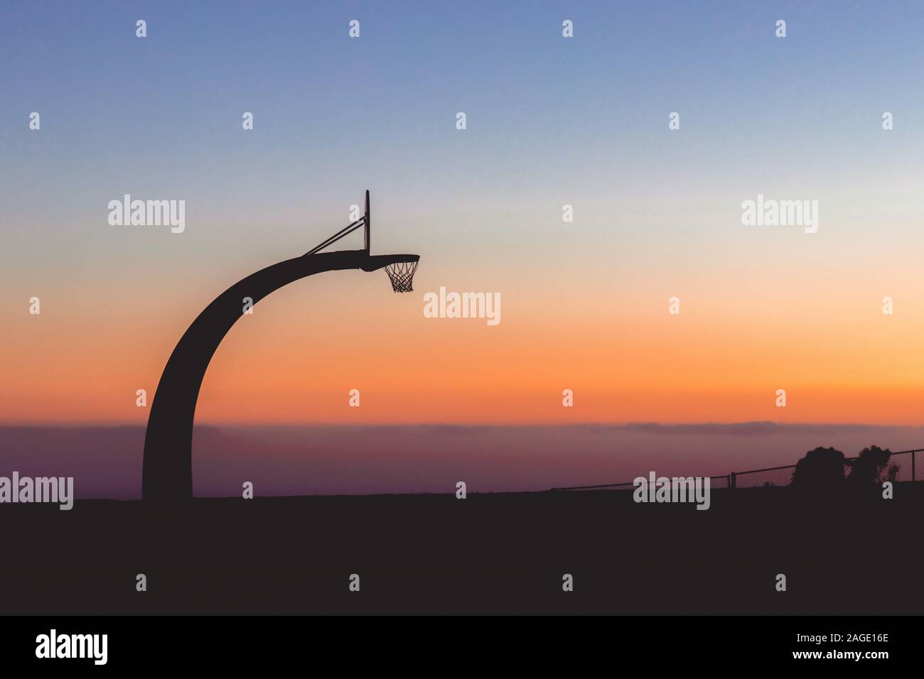 Silhouette of a basketball hoop with the beautiful view of sunset in the background Stock Photo
