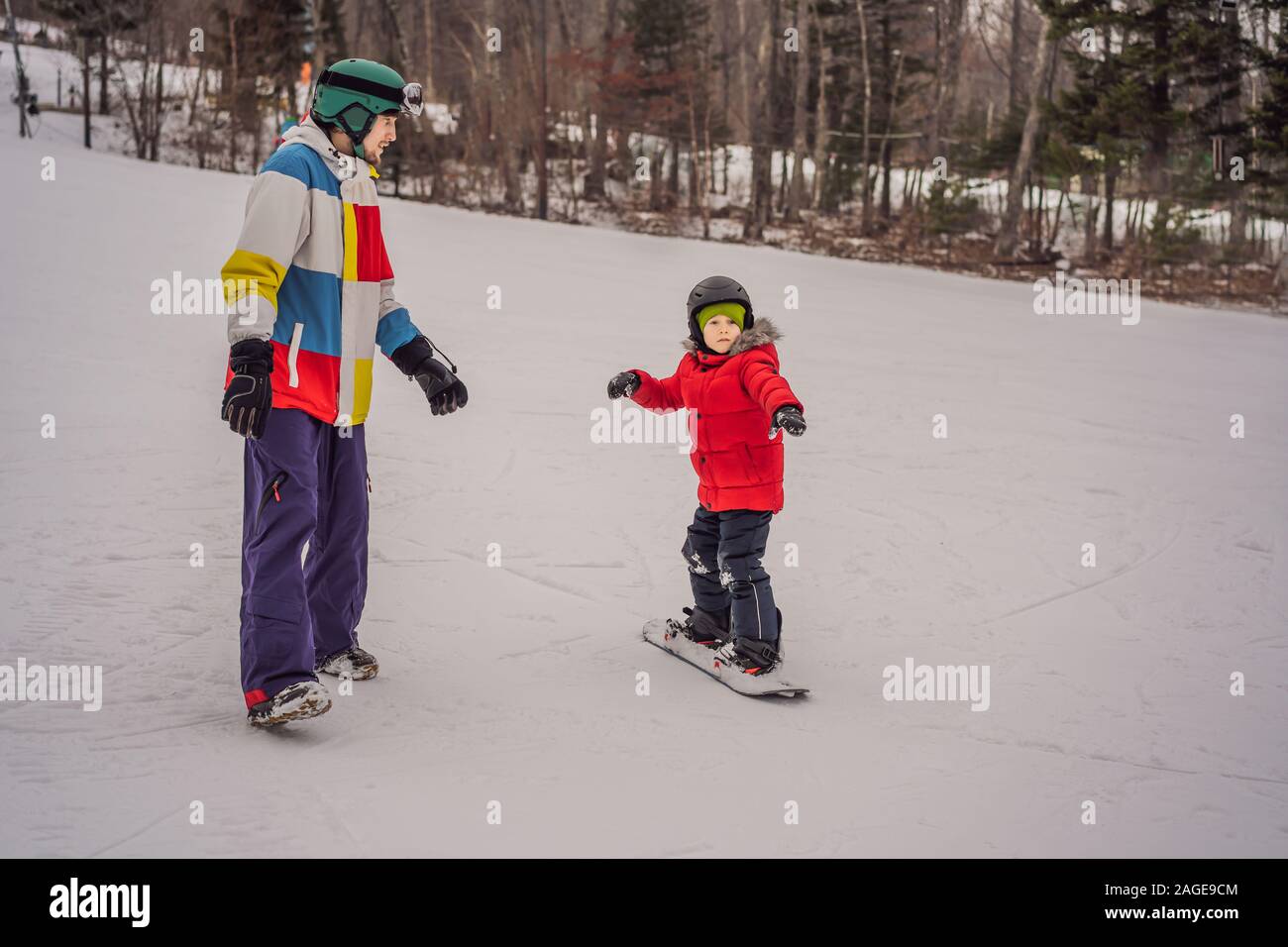 Snowboard instructor teaches a boy to snowboarding. Activities for children in winter. Children's winter sport. Lifestyle Stock Photo