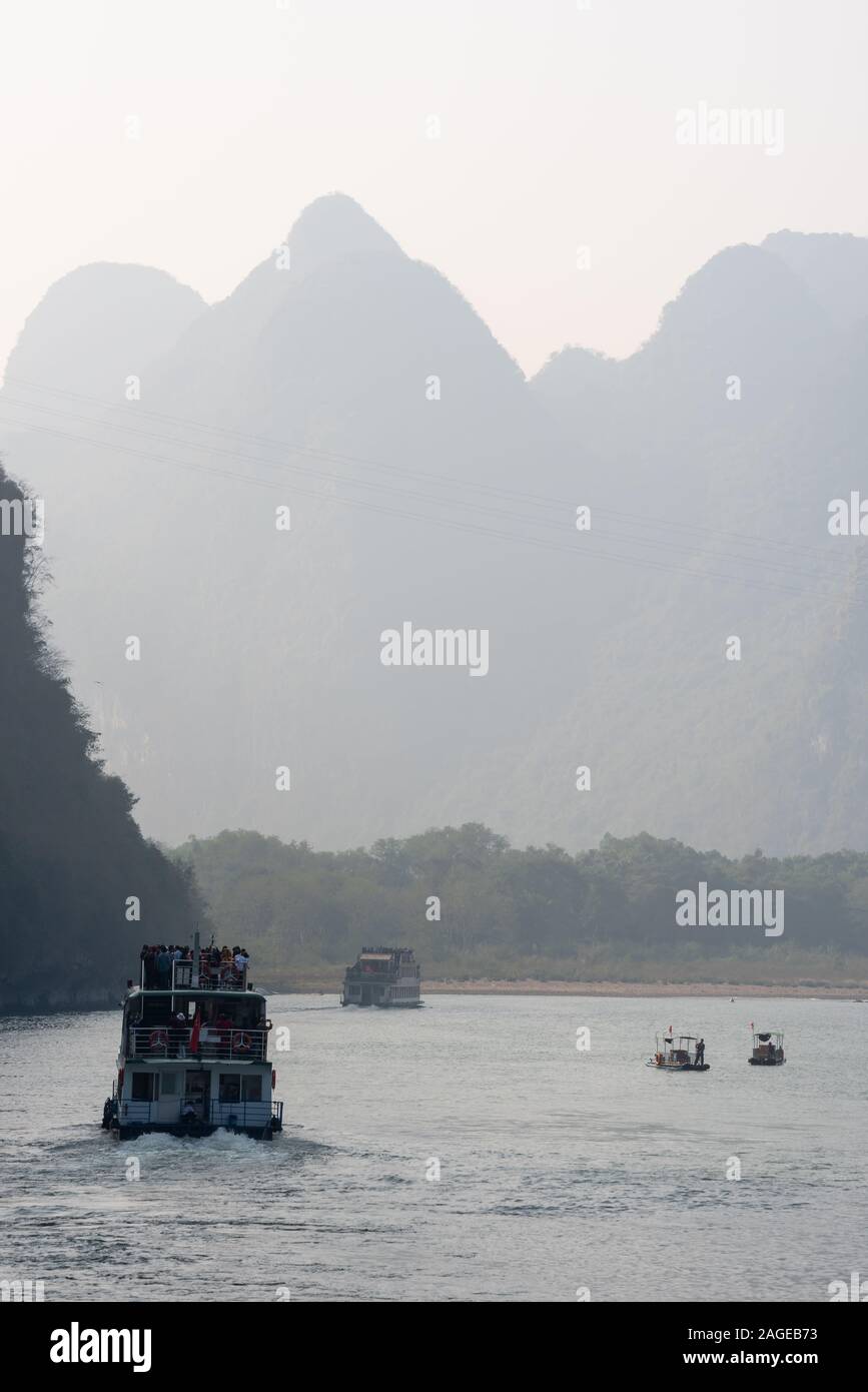 Boat on Li river cruise and karst formation mountain landscape in the fog between Guiling and Yangshuo, Guangxi province, China Stock Photo